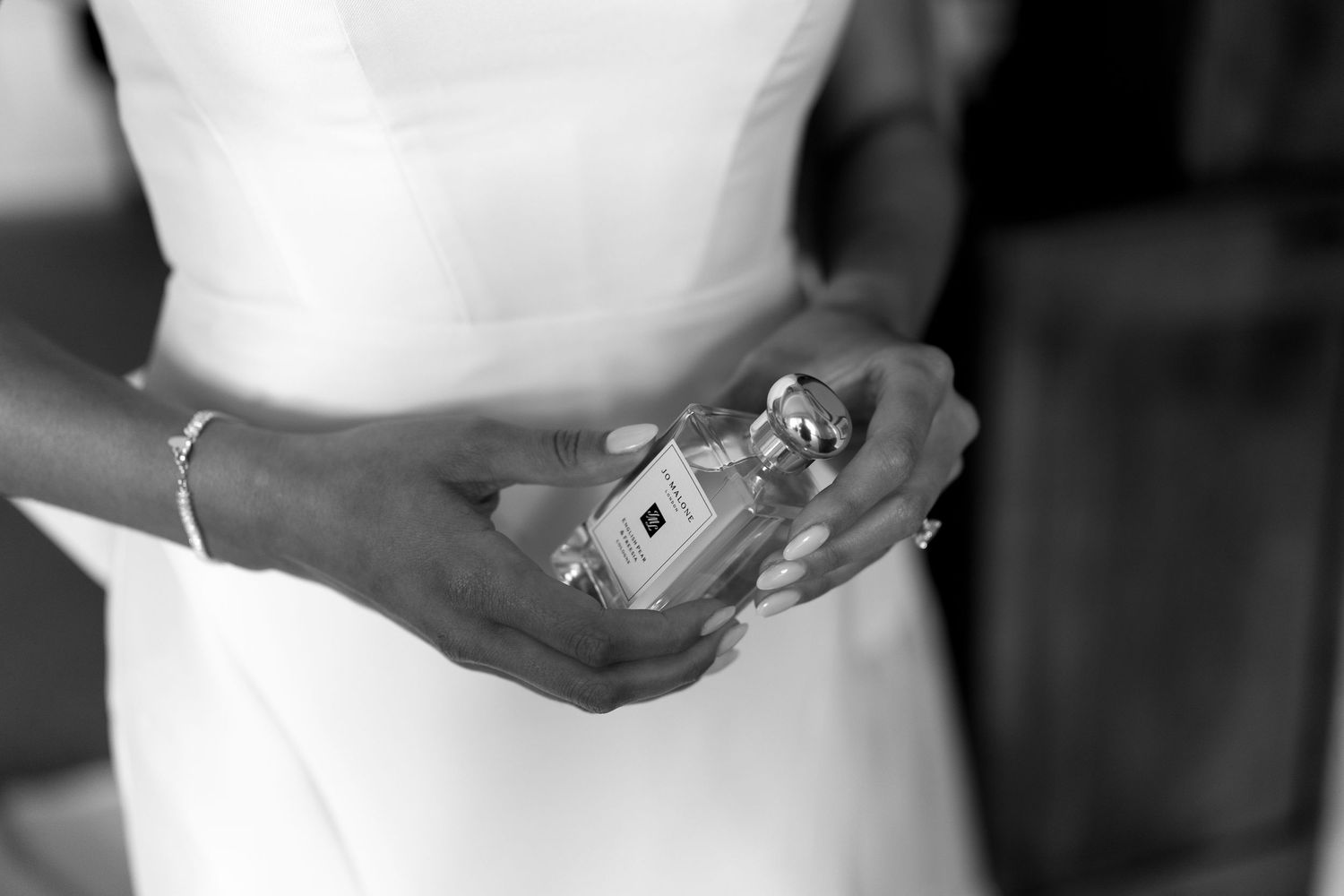 Close-up details of wedding accessories and perfume bottles in black and white.