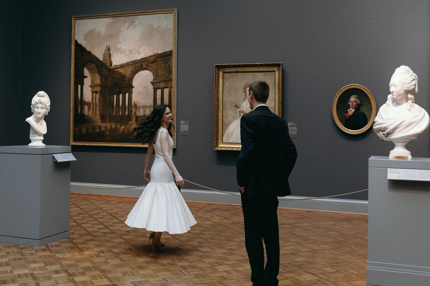 Two people admire classical artwork and busts in an elegant museum gallery. The Chicago Art Institute Engagement Inspiration