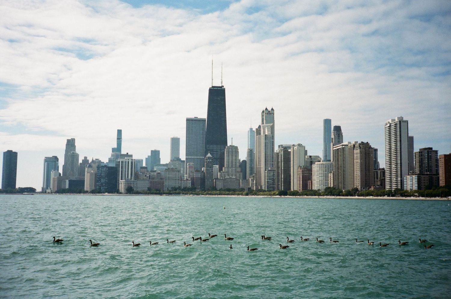 Chicago skyline view from Lake Michigan with skyscrapers reflecting in turquoise waters.