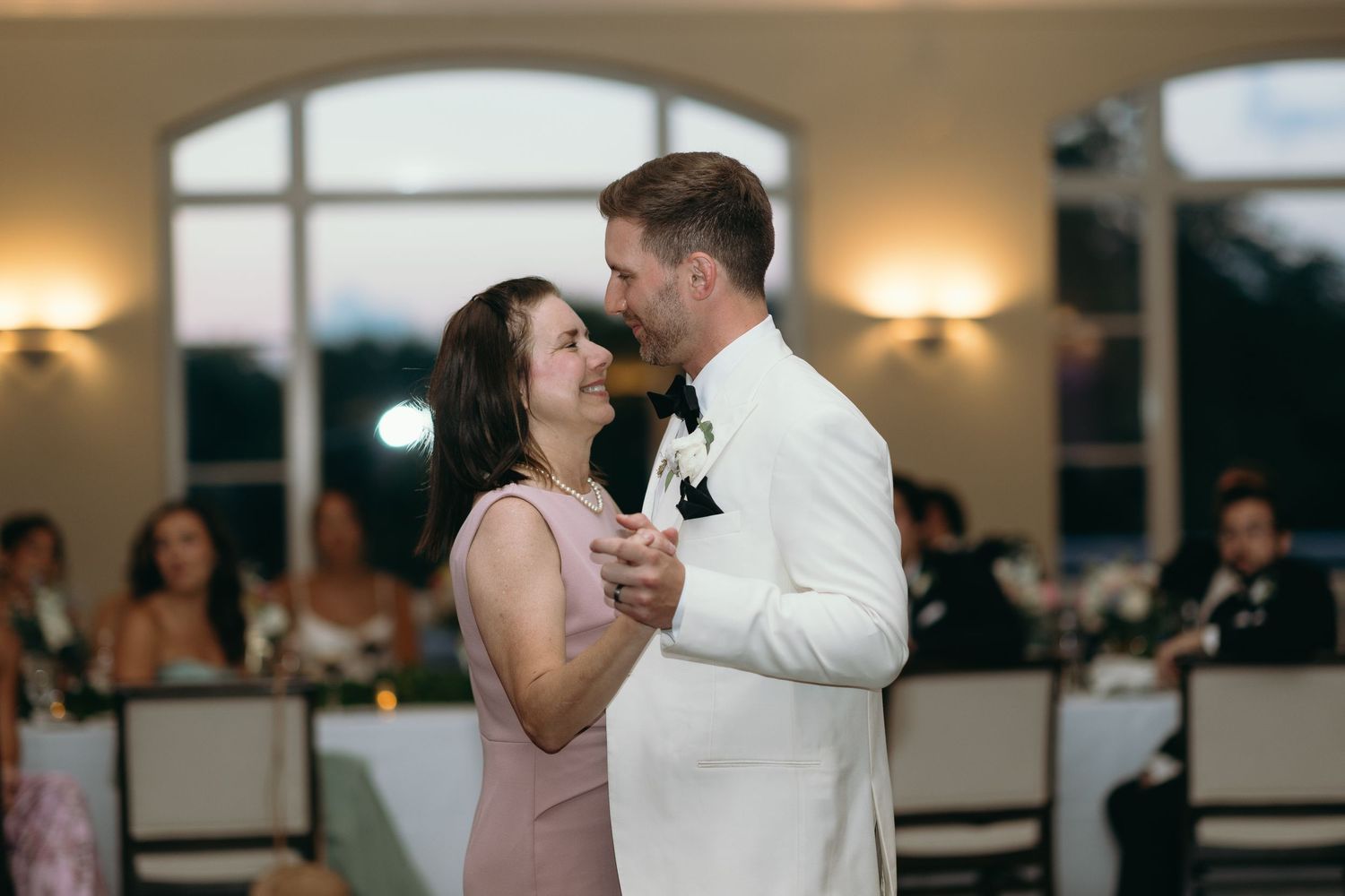 Laughing guests enjoying dinner at a wedding reception with mood lighting.