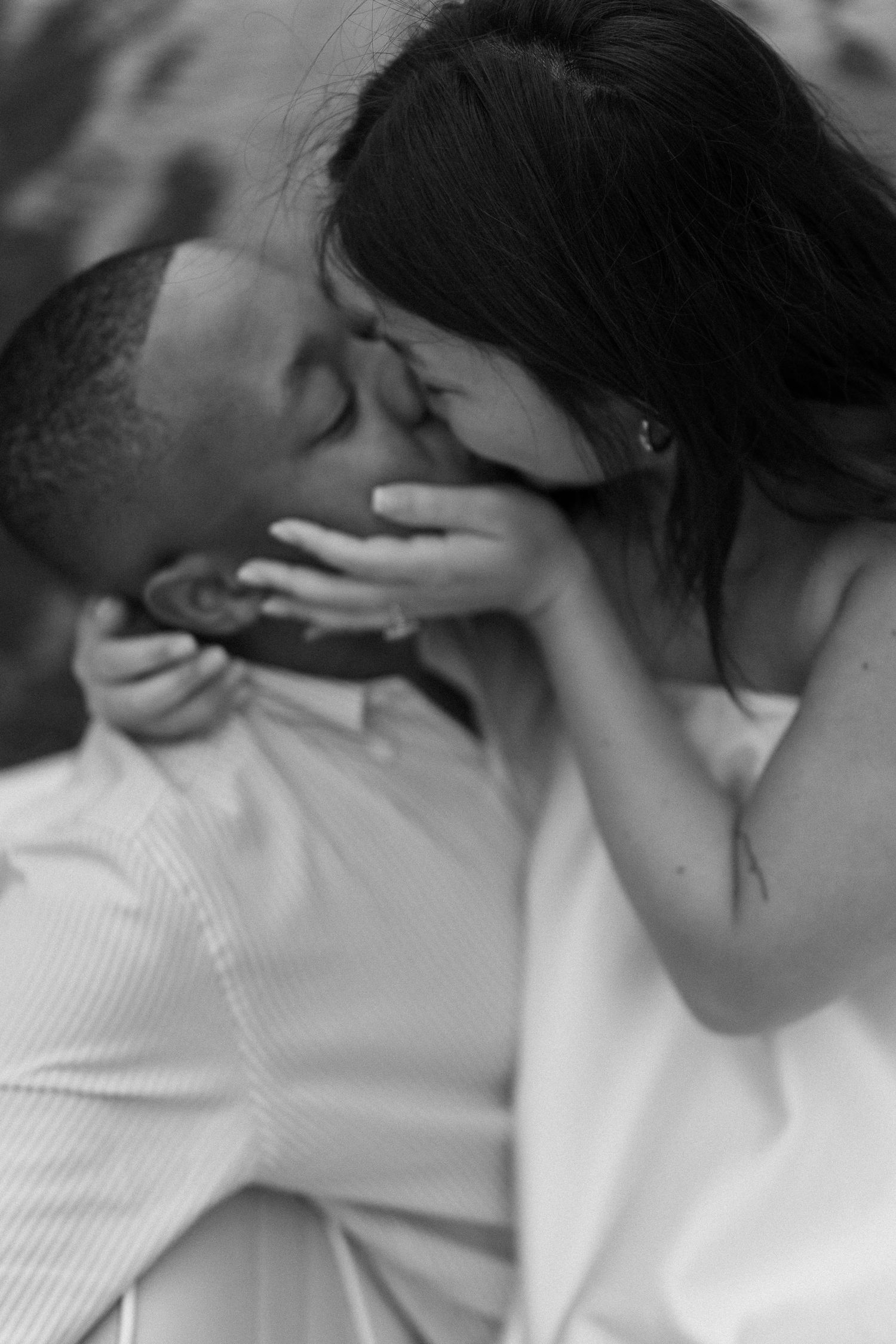 Black and white photo of a couple sharing a romantic kiss, the woman tenderly holding the man's face.