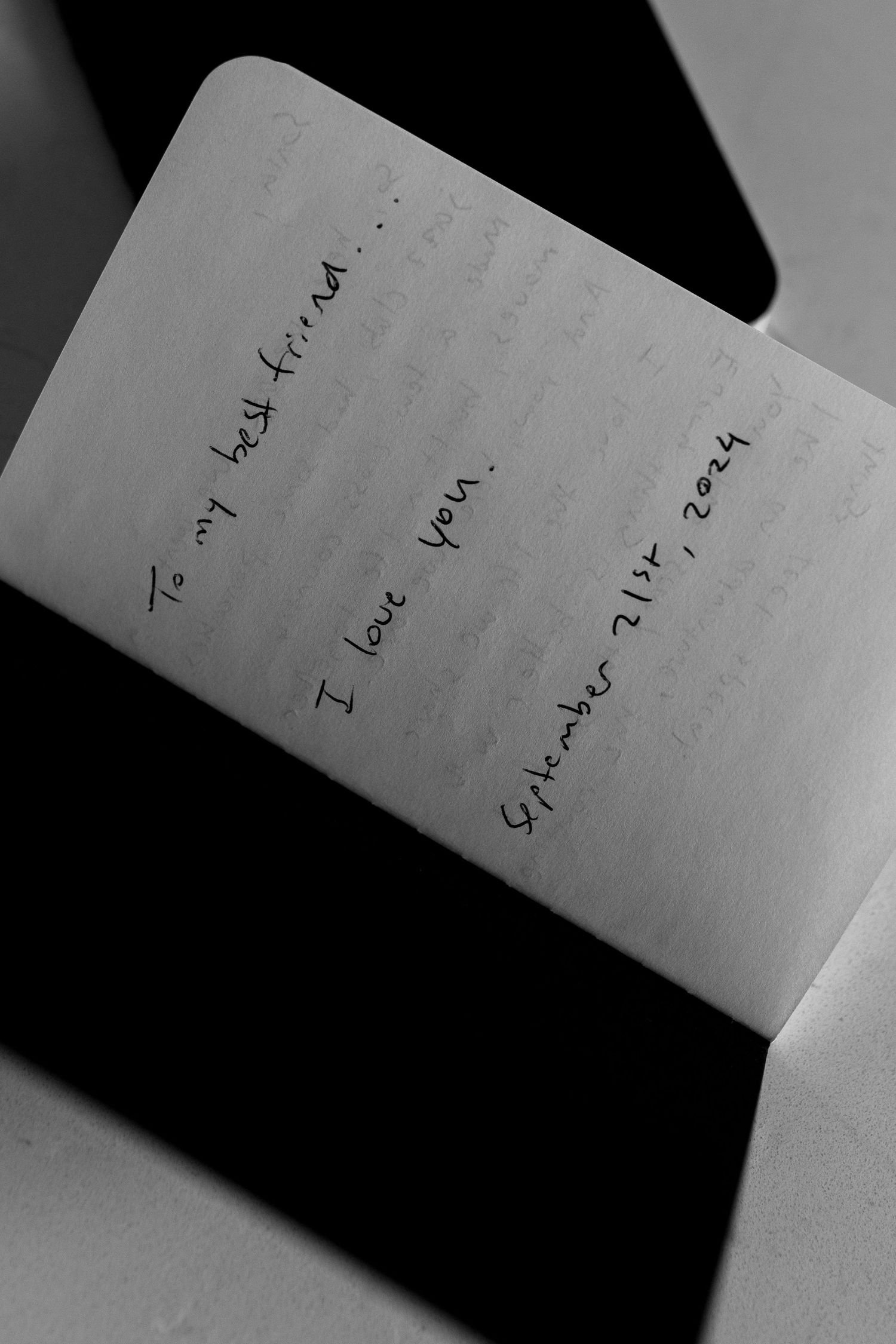 Handwritten note on a white notebook page captured in black and white.