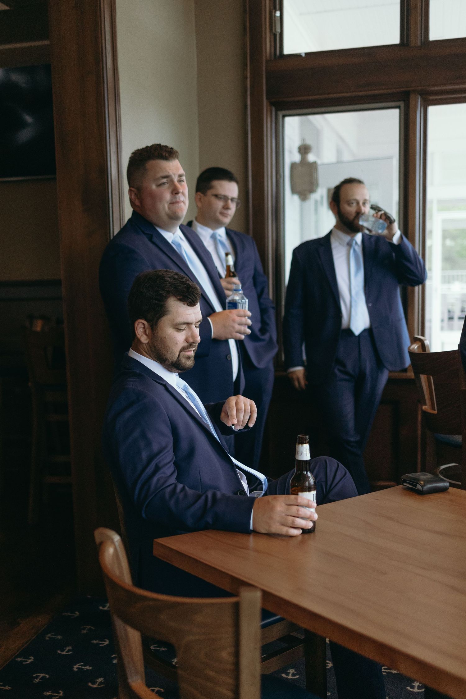 A series of six photos showing a group in navy suits drinking beverages at a wooden conference table.