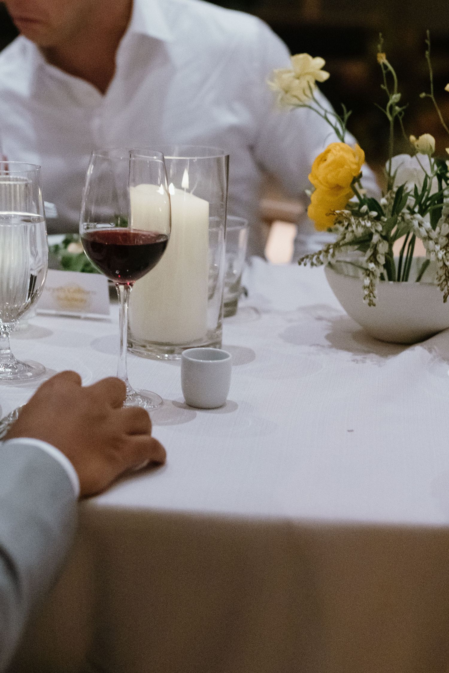 Elegant table setting with white linens, glassware and delicate floral centerpieces.