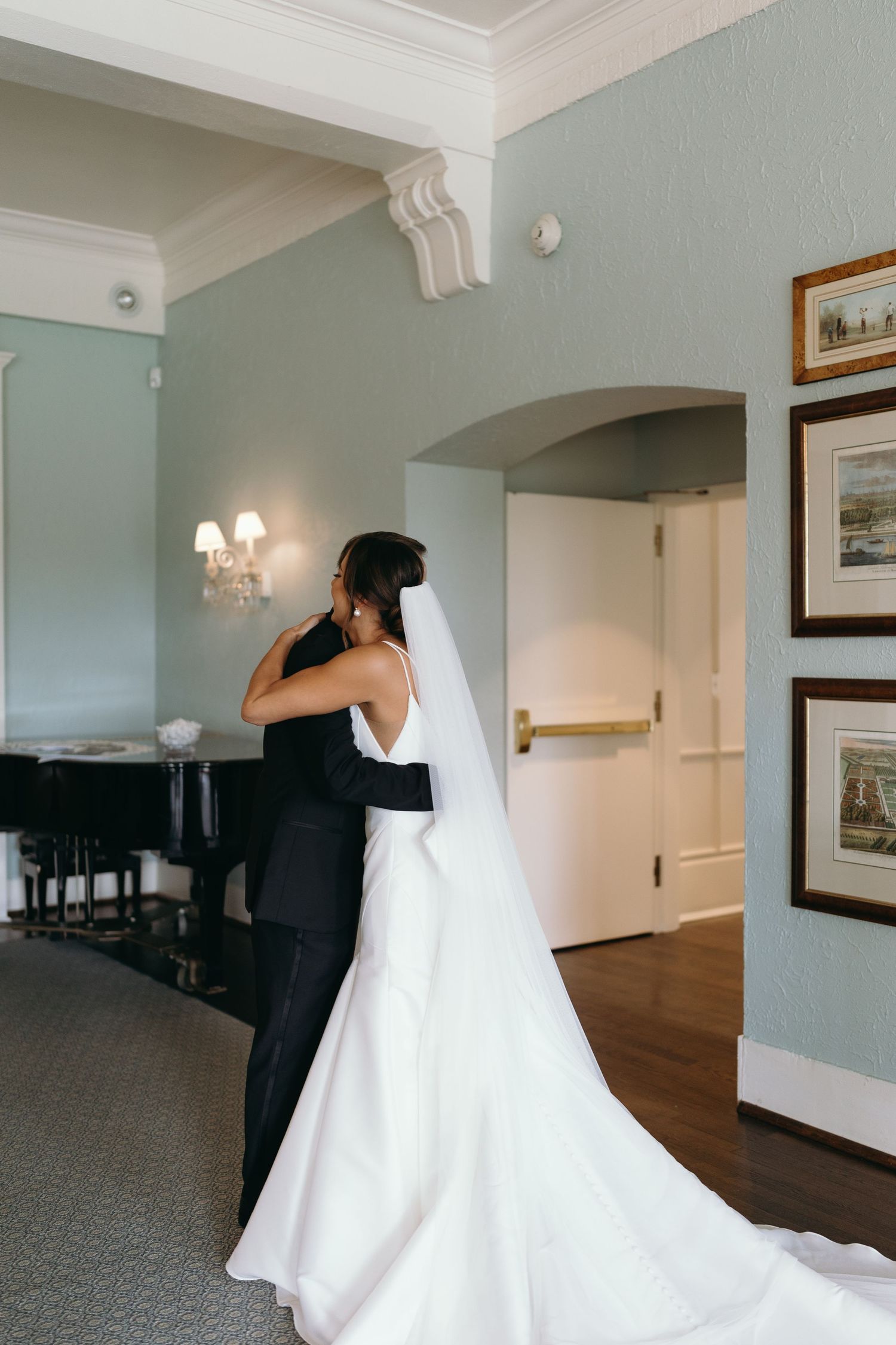 Wedding party getting ready in an elegant hotel hallway with white walls and framed artwork.
