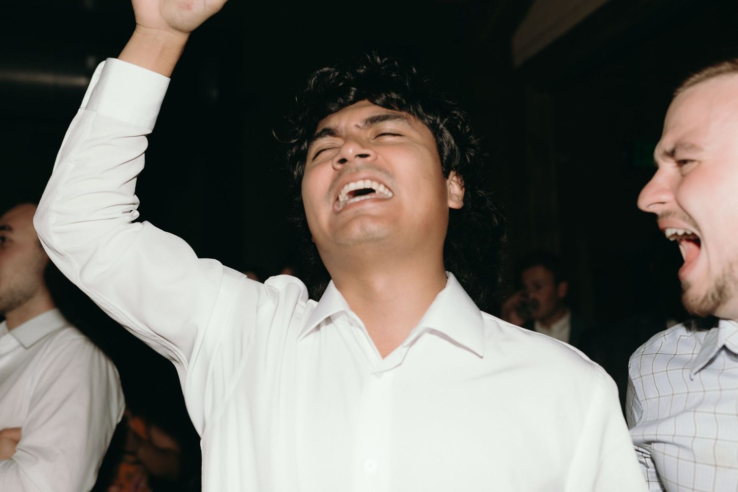 Joyful wedding guest with raised fist celebrating and dancing at lively wedding reception.