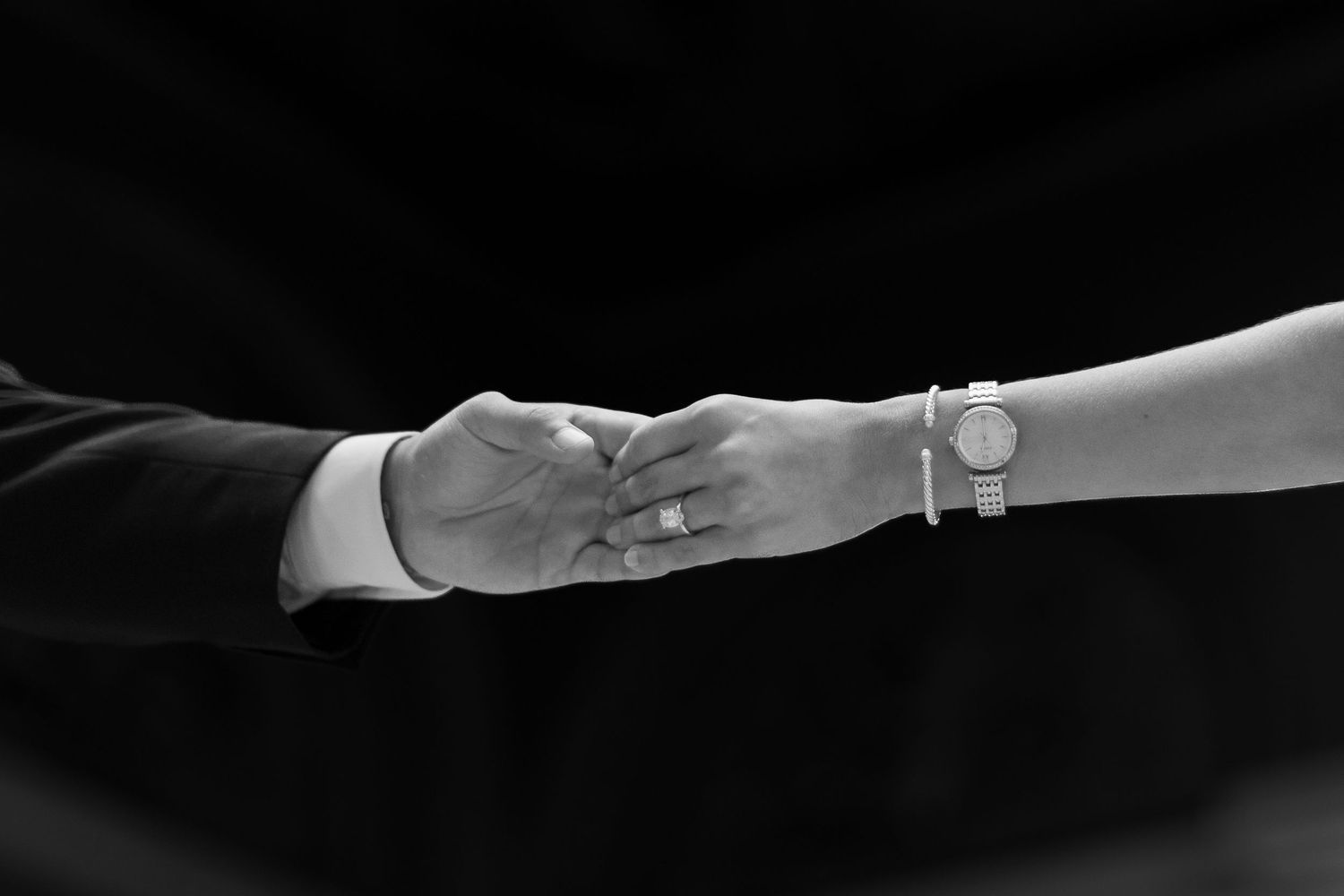 A pair of white satin bridal gloves gracefully posed against a dark background.
