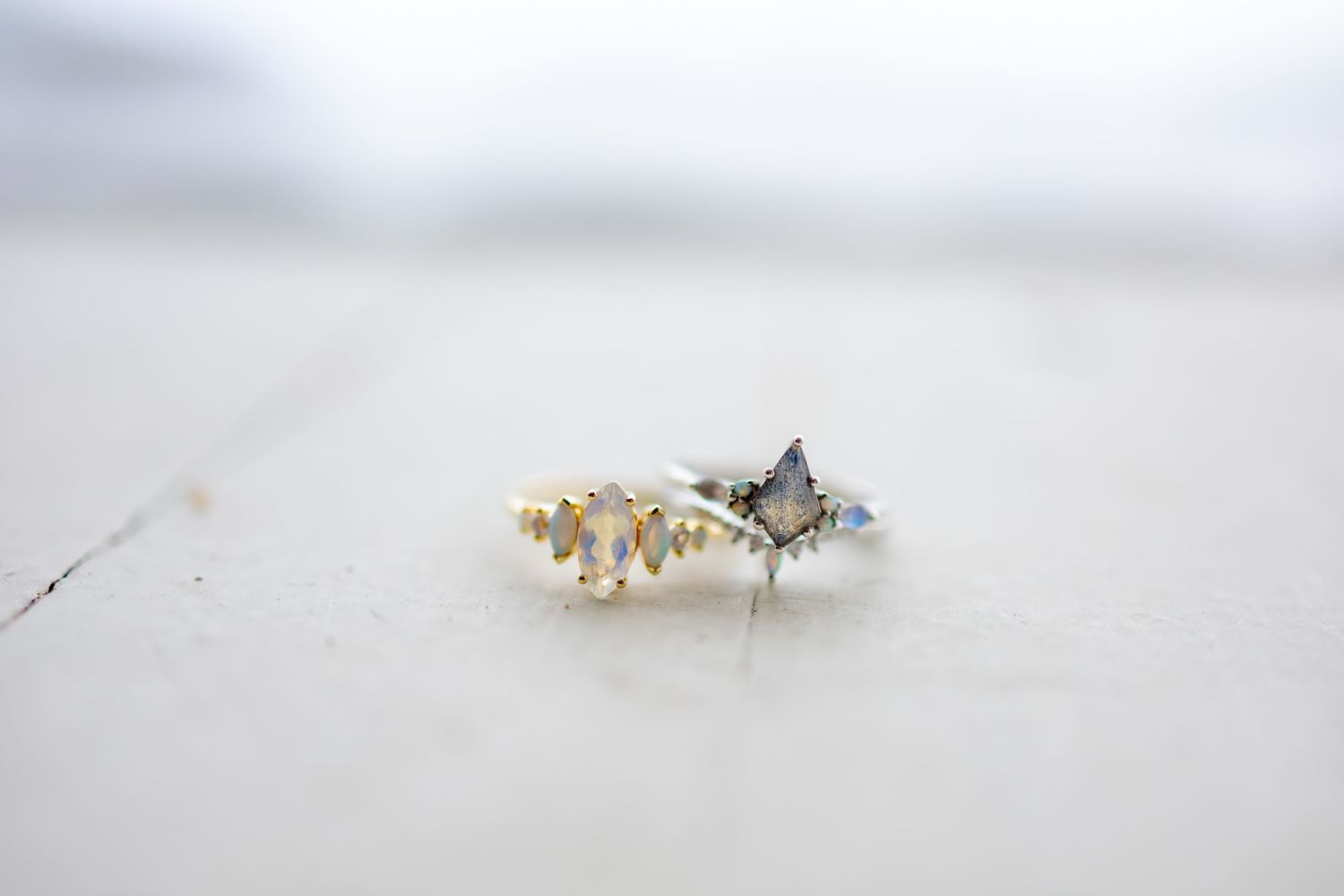 Delicate engagement ring with pearl details photographed on light background.