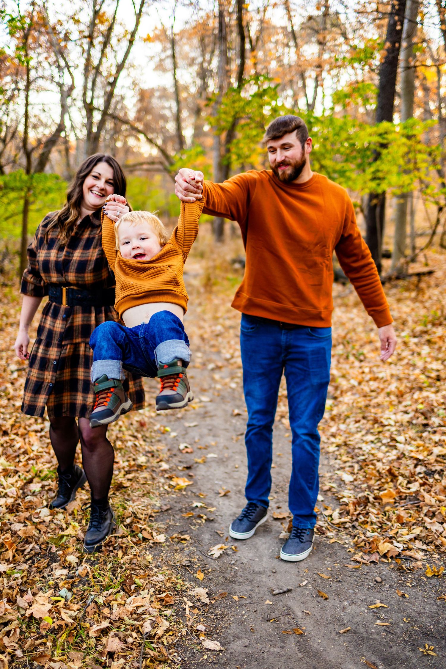 A playful family walking through autumn leaves wearing coordinated orange and blue outfits.