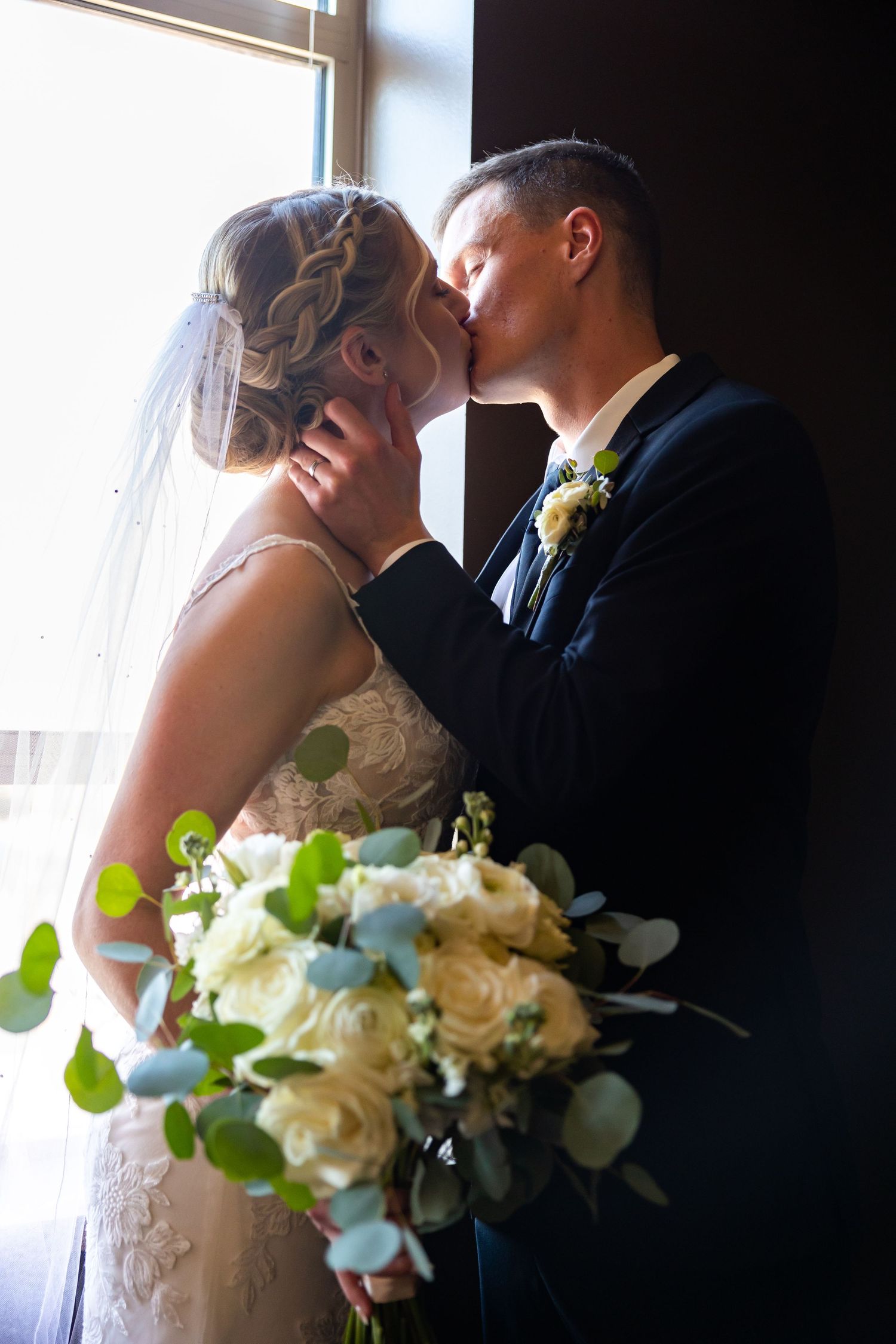 Intimate wedding portrait by window with white rose and eucalyptus bouquet.