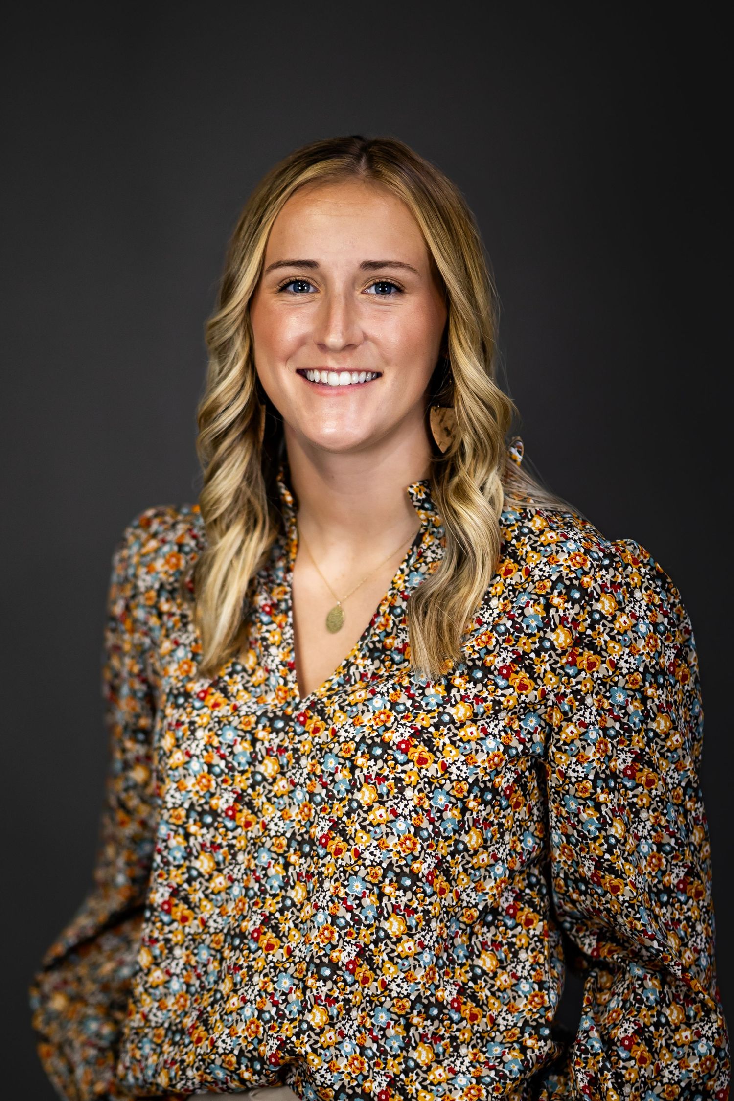 Professional portrait series featuring someone in a floral print blouse against a dark backdrop.