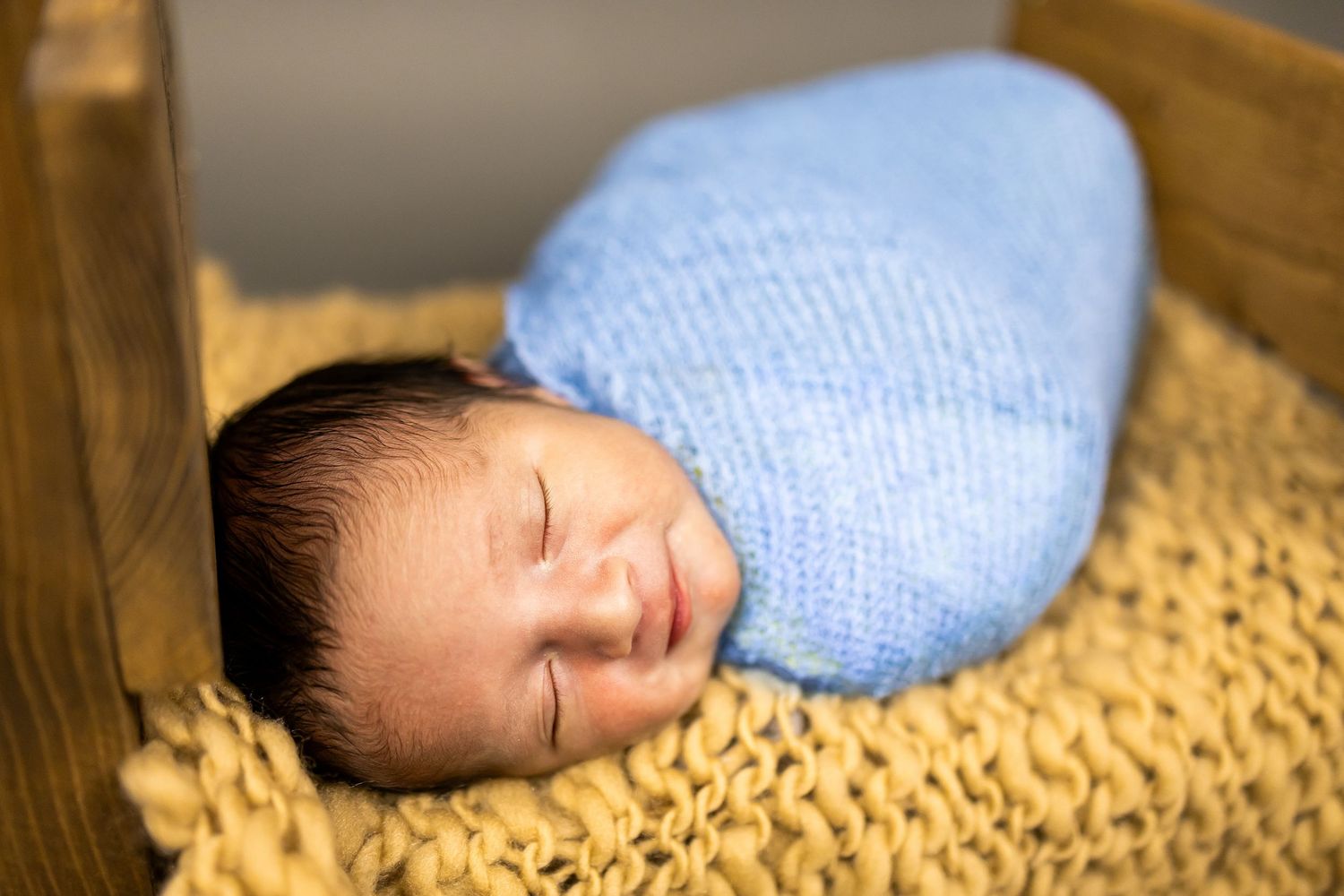 Infant sleeping peacefully on a textured yellow blanket wearing a light blue outfit.
