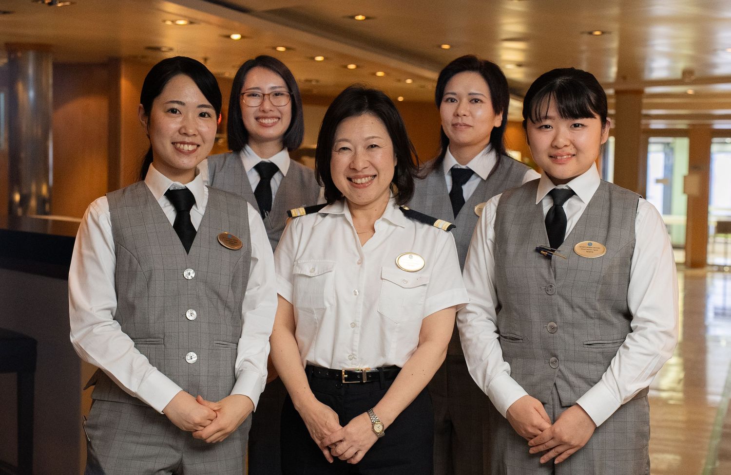 Hotel staff members in professional uniforms stand together in a group photo showing teamwork and hospitality.