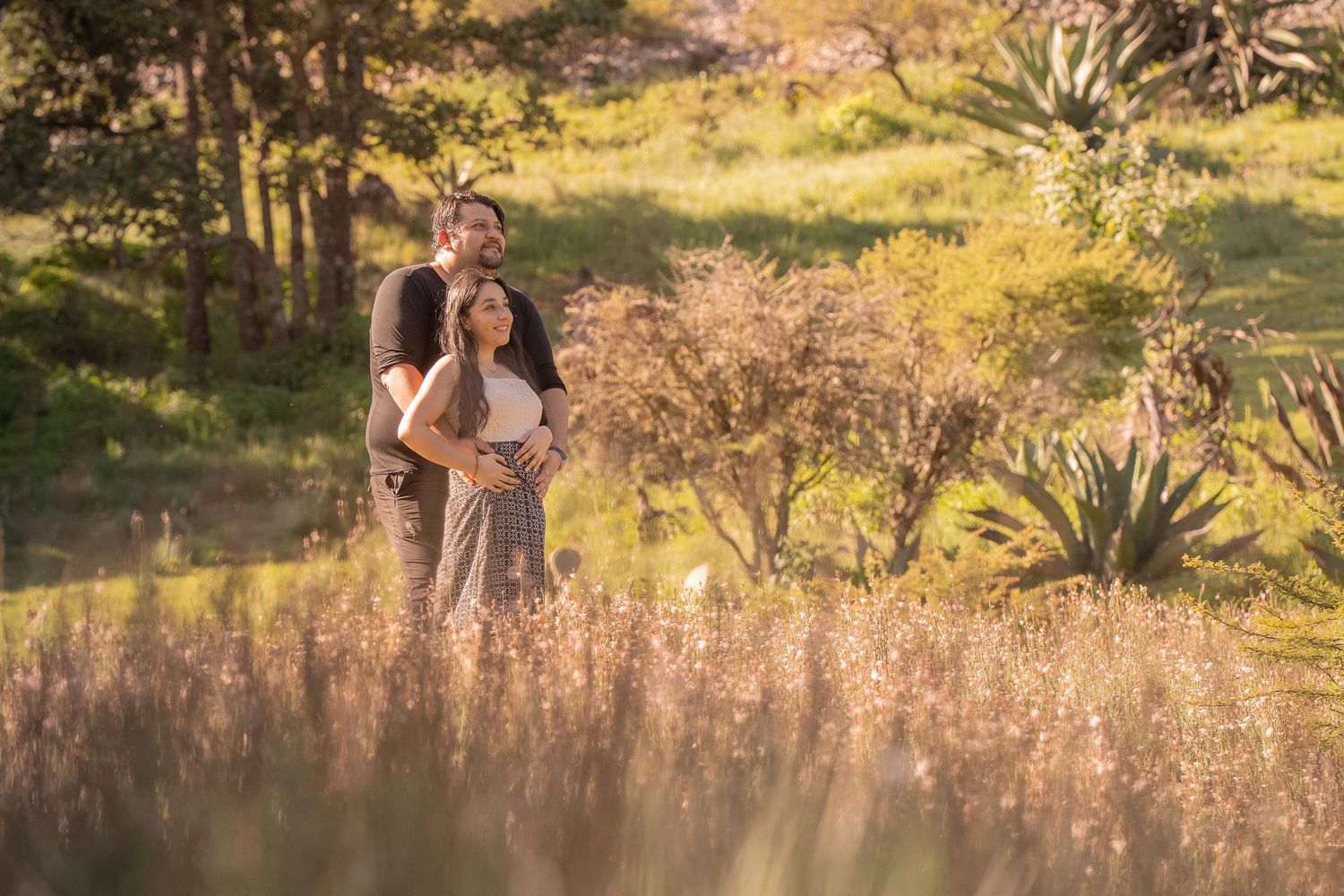 Partners dance through tall grass in a scenic outdoor location at sunset.