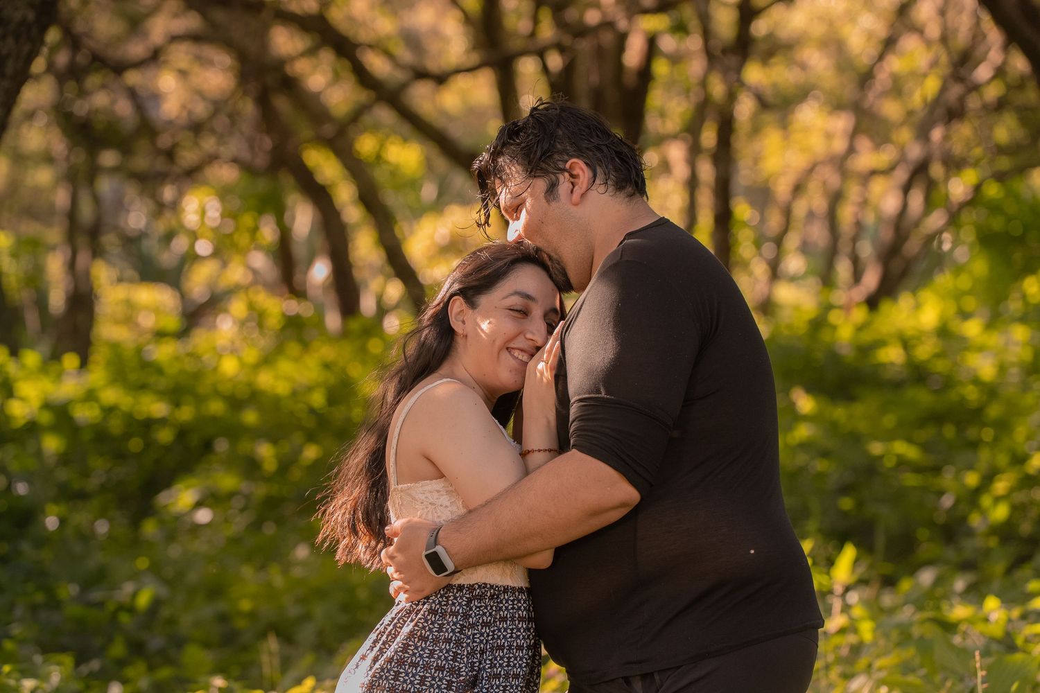 A couple practices dance moves in a lush forest setting with dappled sunlight.