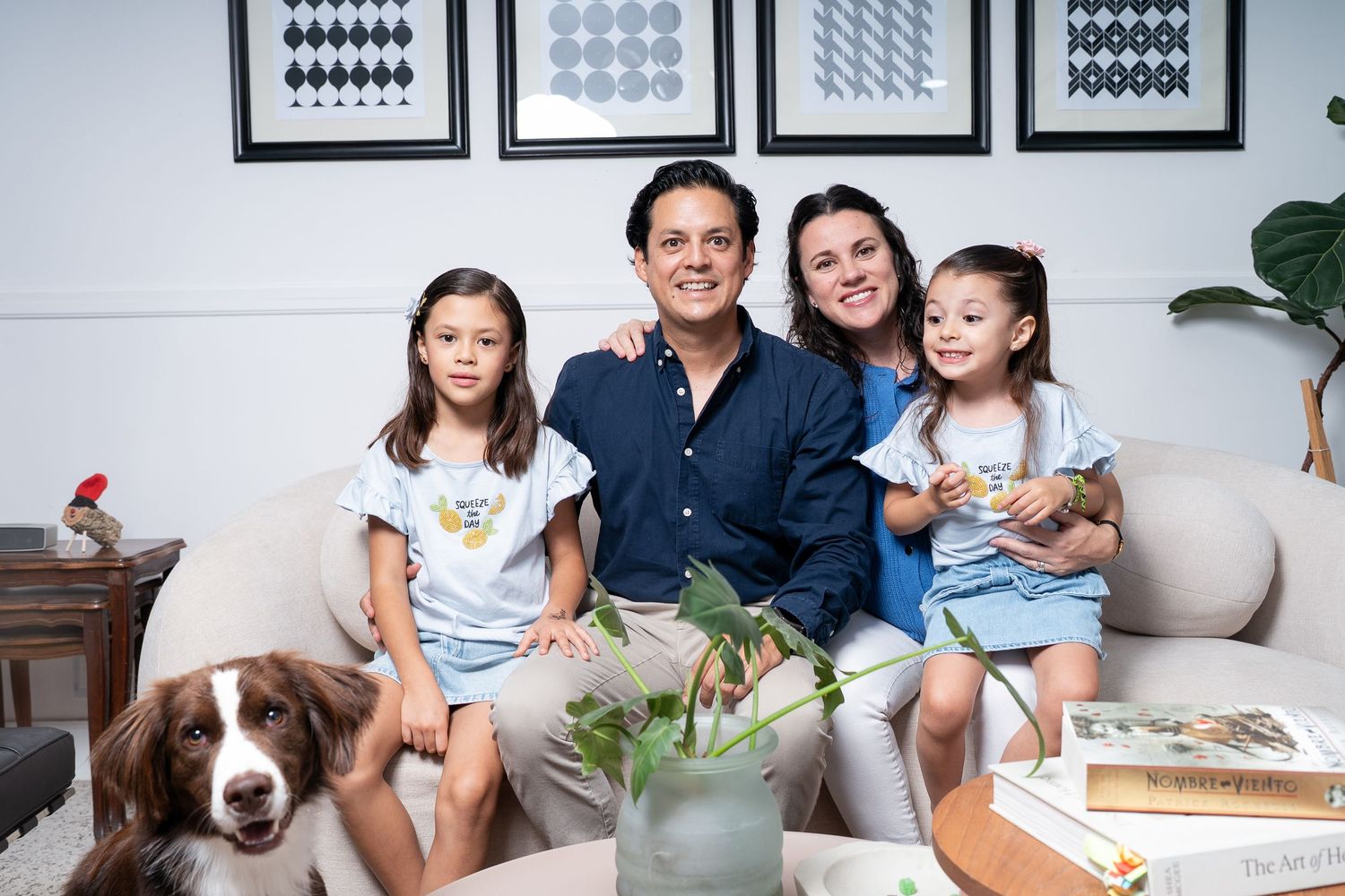 A modern family portrait in a bright room with minimalist decor and framed artwork.