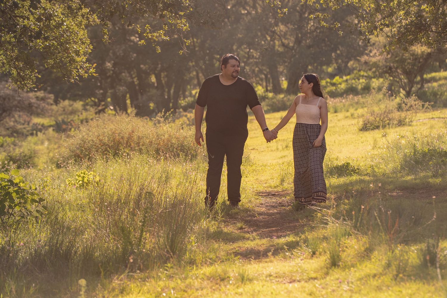 People dance together on a nature trail during a golden sunset.