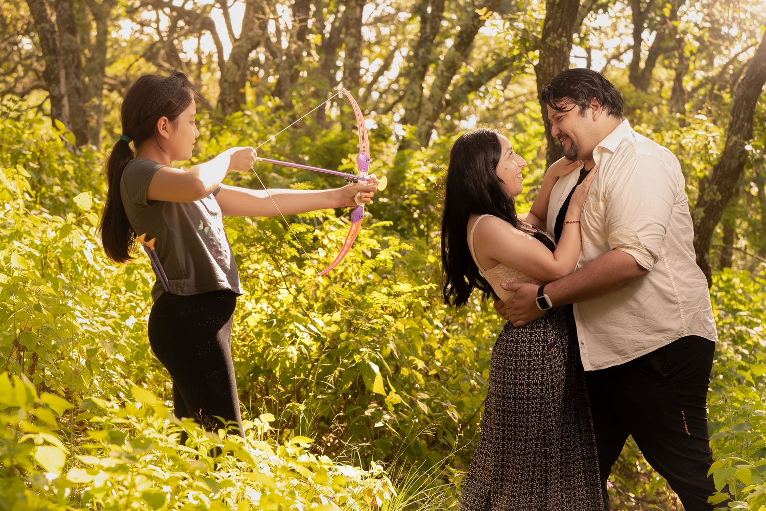 Dancers practice their moves in a wooded area with warm sunlight filtering through trees.