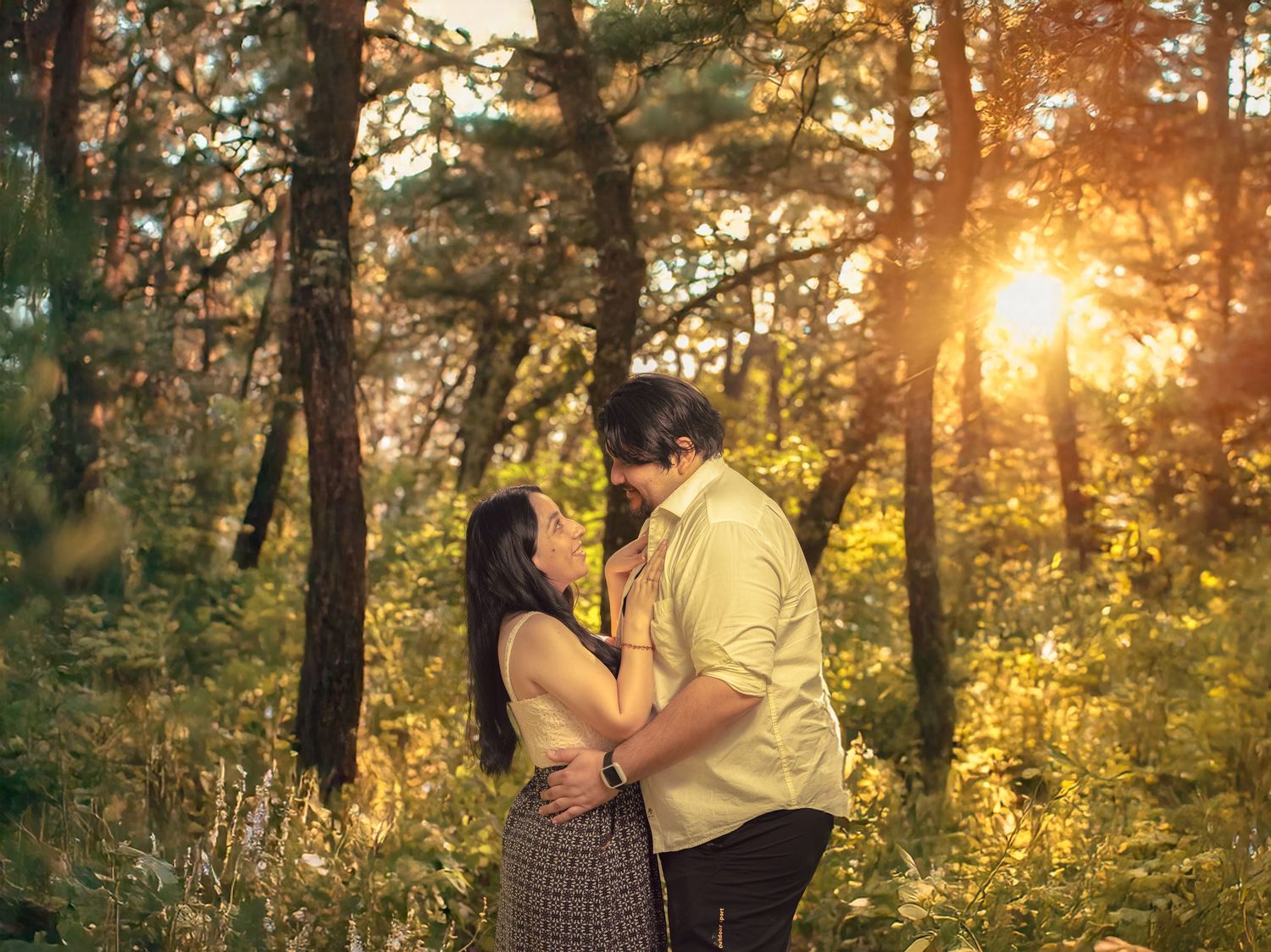 A couple shares a romantic moment in a forest backlit by golden sunset rays.