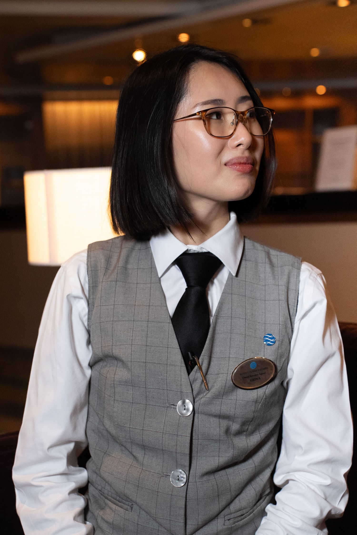 Staff member in uniform checking their phone in a well-lit indoor space.