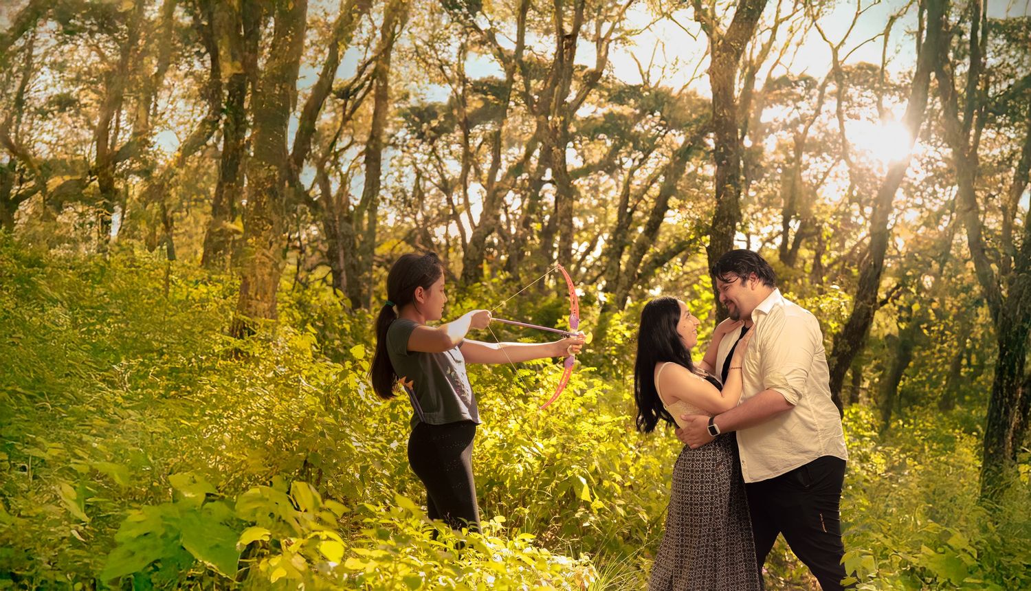A couple dances together in a sunlit forest clearing during golden hour.