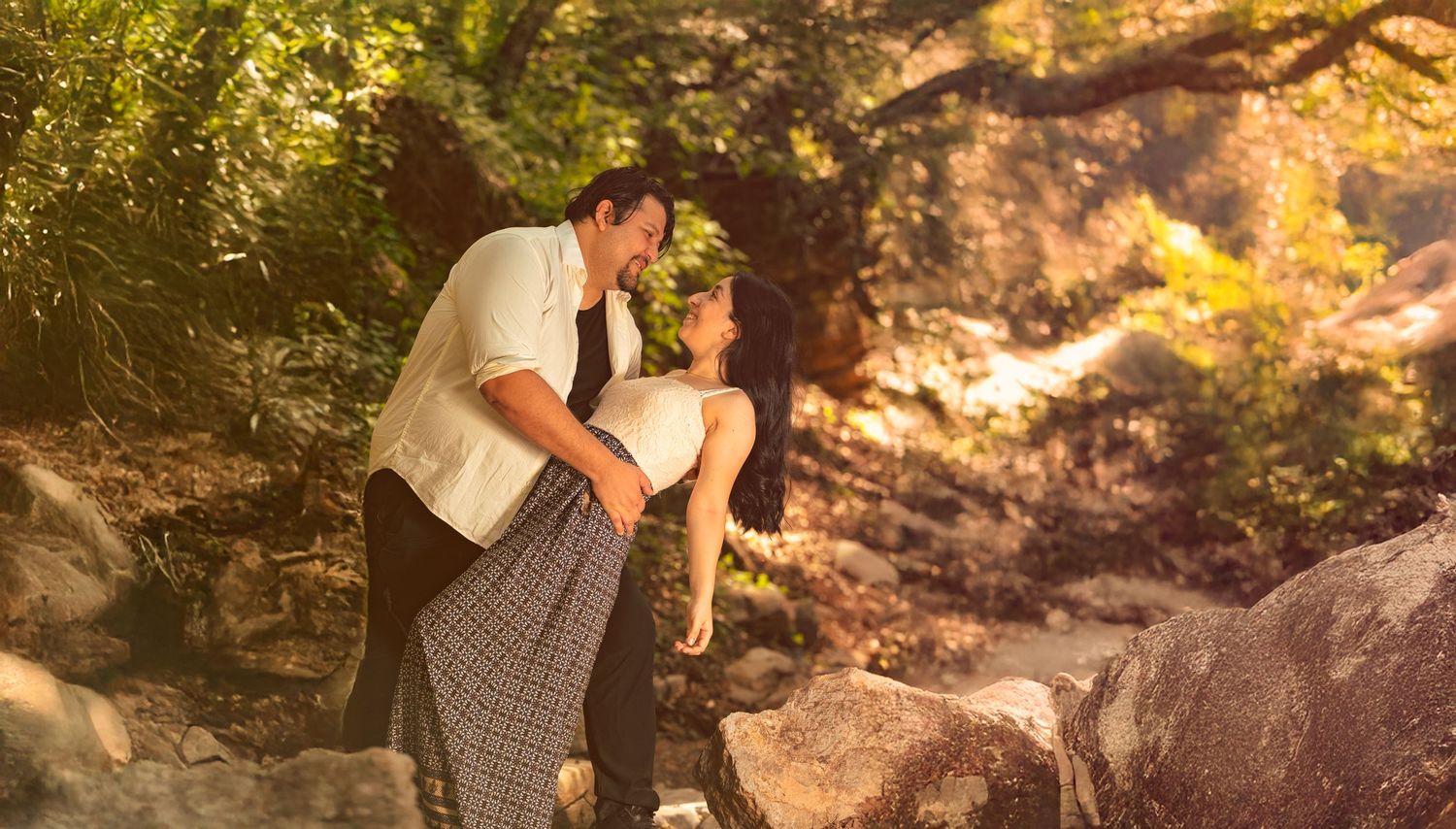Dancers strike elegant poses against rocky terrain in warm evening light.