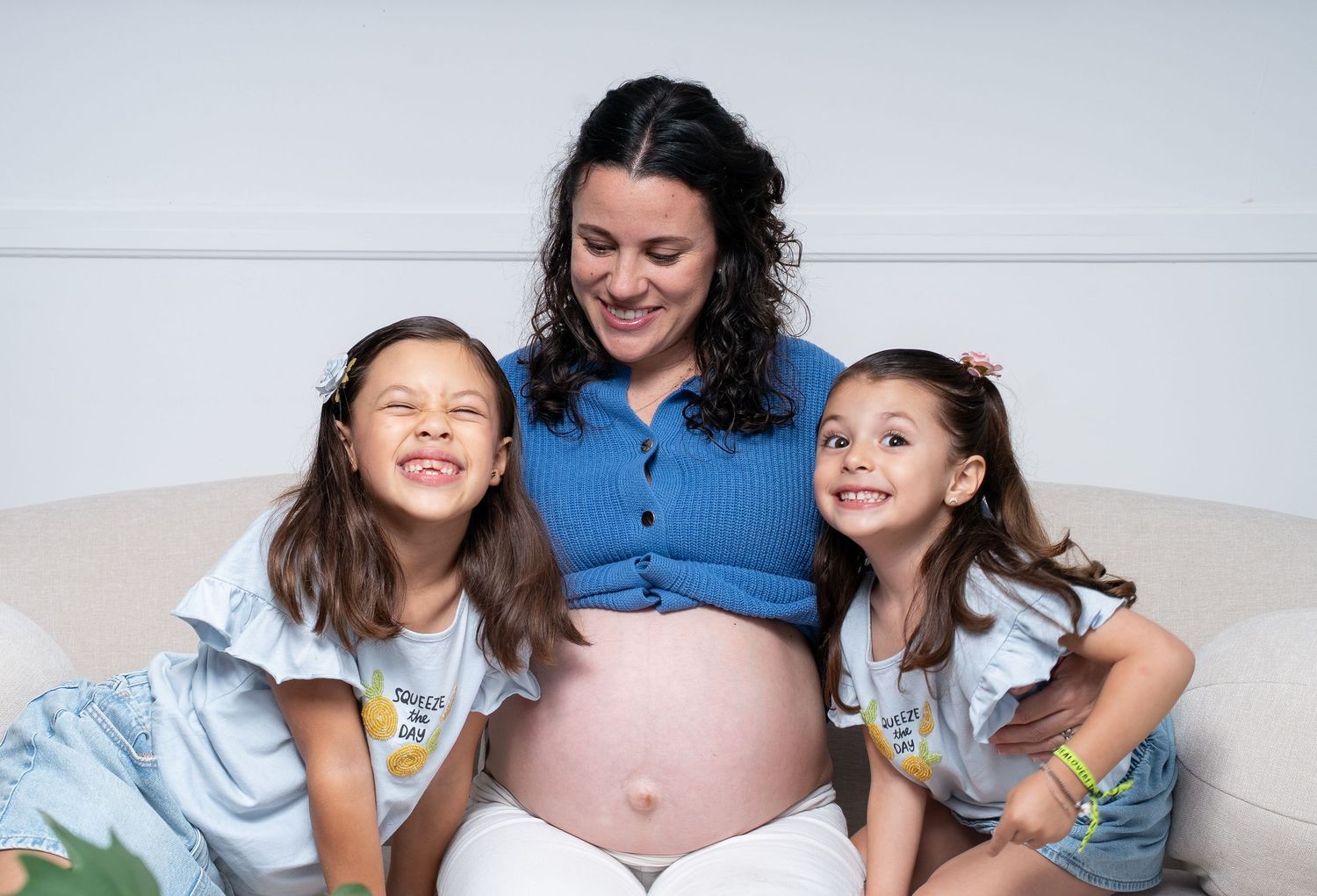 A family gathers around a pregnant woman's belly for a candid maternity photo.