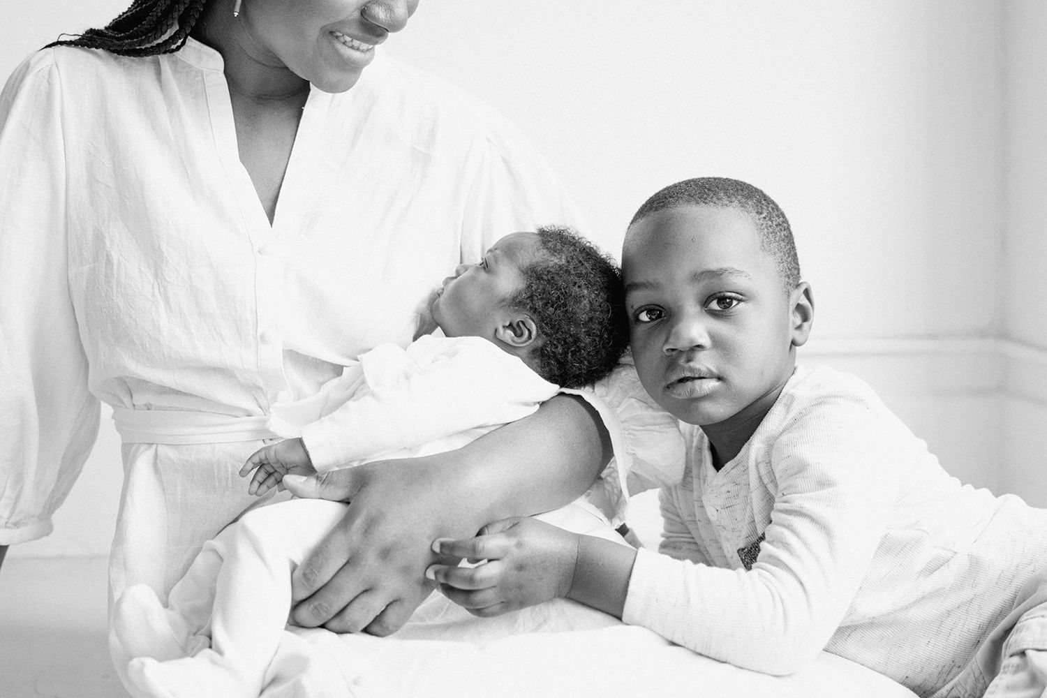 Four black and white images of a baby getting a gentle medical examination in a medical setting.