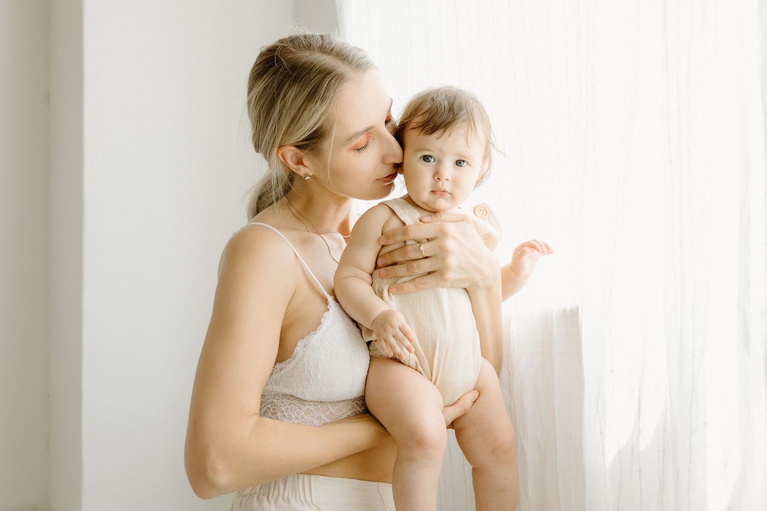 Gentle bonding moments between parent and baby in a bright, white interior space.