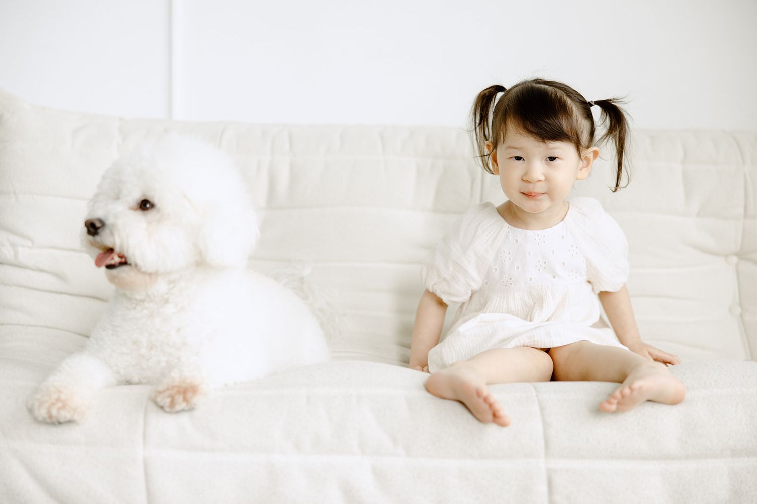 A series of soft white minimalist photos showing a small baby on white bedding in various peaceful resting poses.
