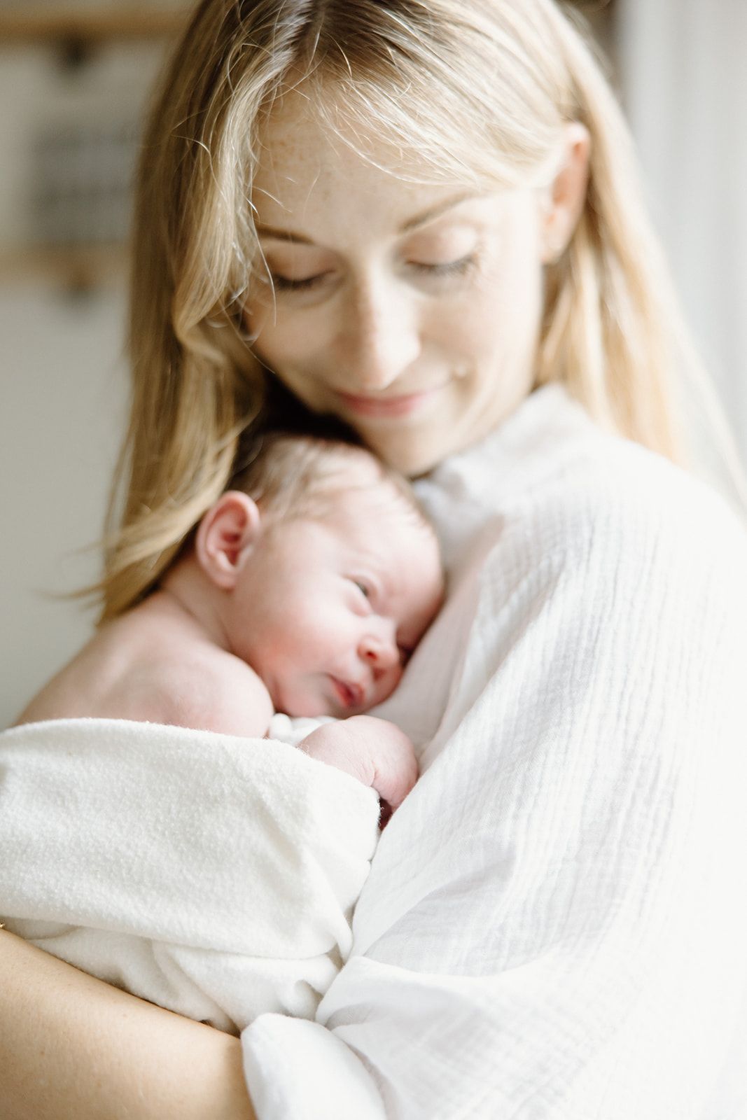 Intimate family photos in soft natural light against white bedding.