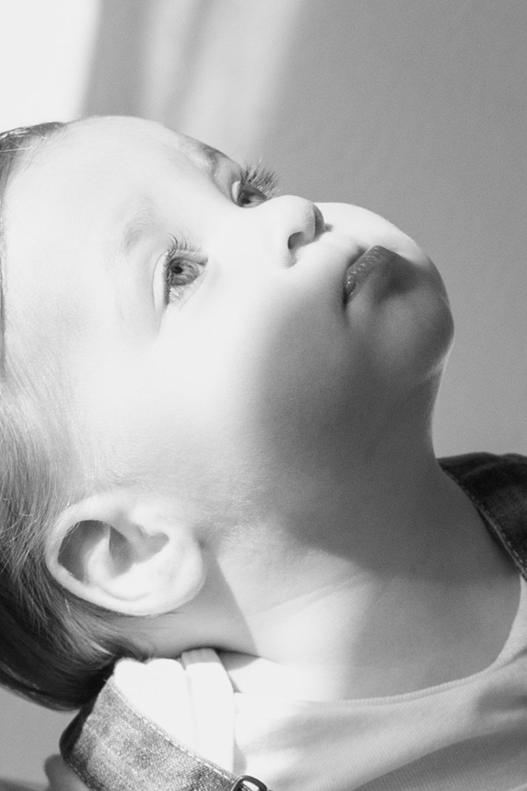 Black and white artistic portrait shot in profile view with upturned face highlighting dramatic lighting and shadows.