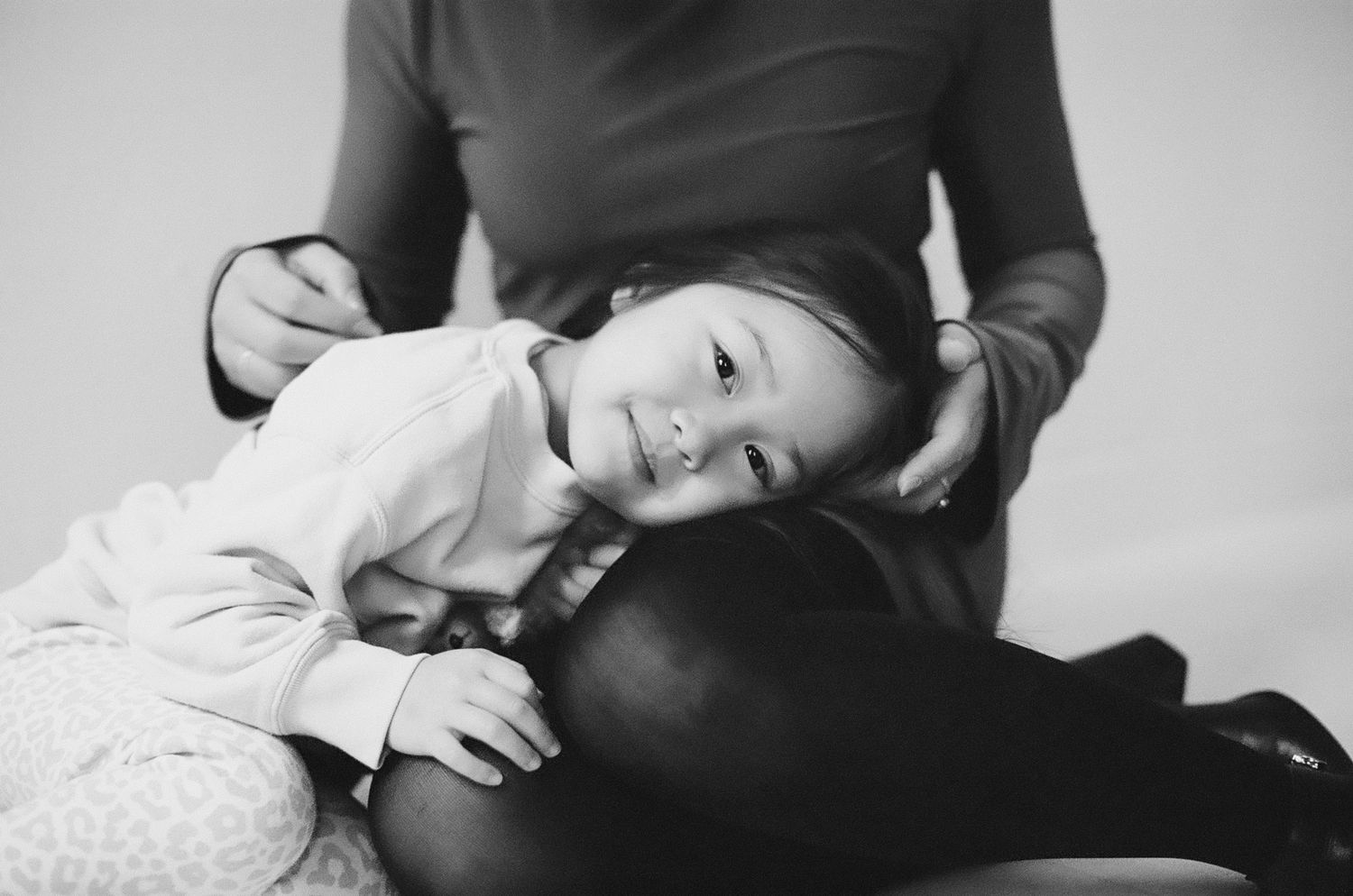 A black and white photo series showing tender moments between a parent and baby in various intimate poses.