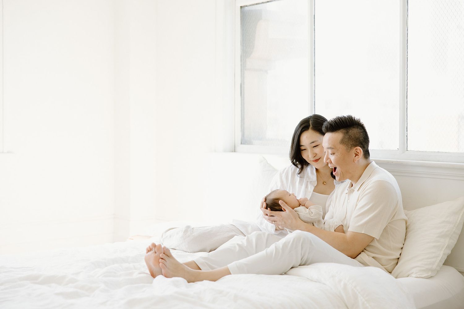 Two people share tender moments while relaxing in a bright white living room setting.