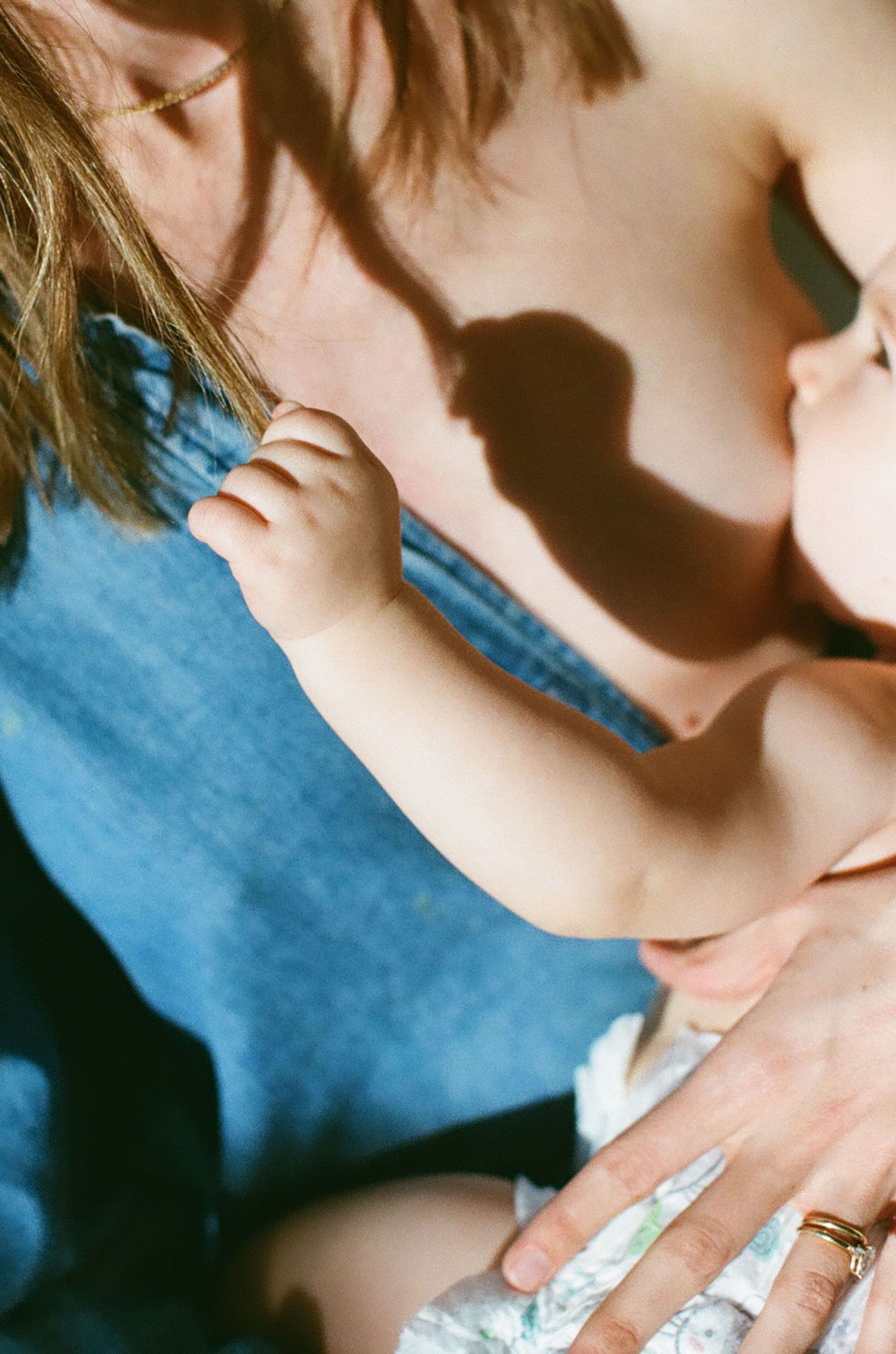 A mother breastfeeding her newborn baby, with soft natural light casting gentle shadows on their skin.