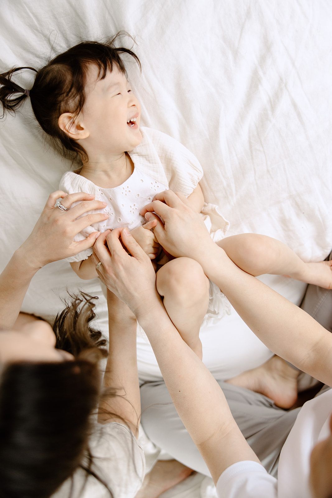 Playful moments captured on white bedding in natural light.