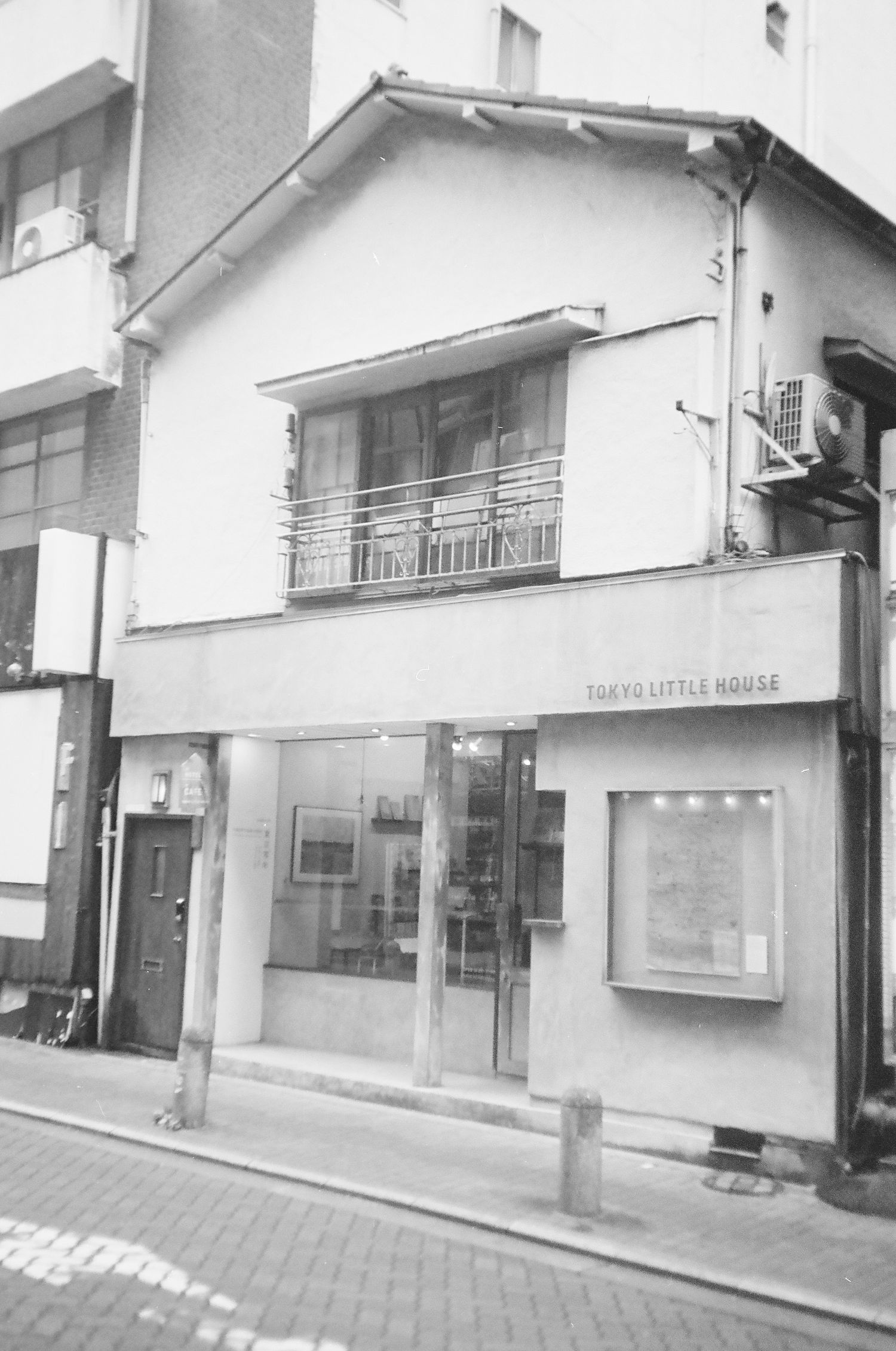Black and white photo of a narrow Japanese building facade with 'Tokyo Letter House' signage and a balcony on the second floor.