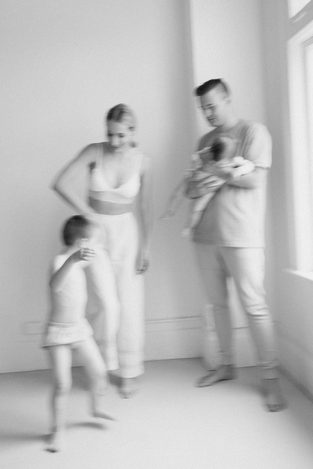 Motion blur photo of people playing and moving in a bright white minimalist room.