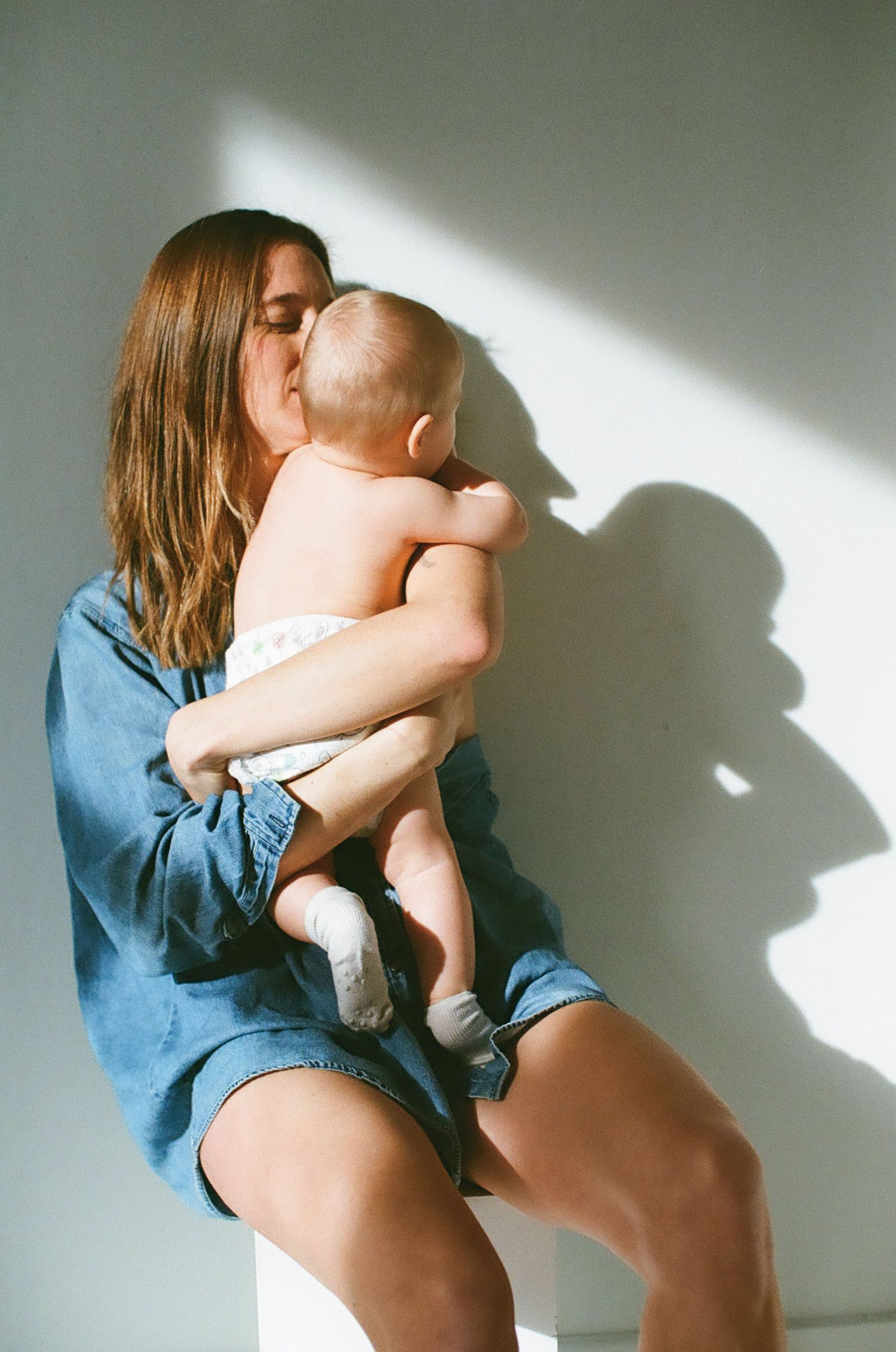 A series of artistic photos showing intimate shadows and silhouettes against a white wall with denim clothing details.