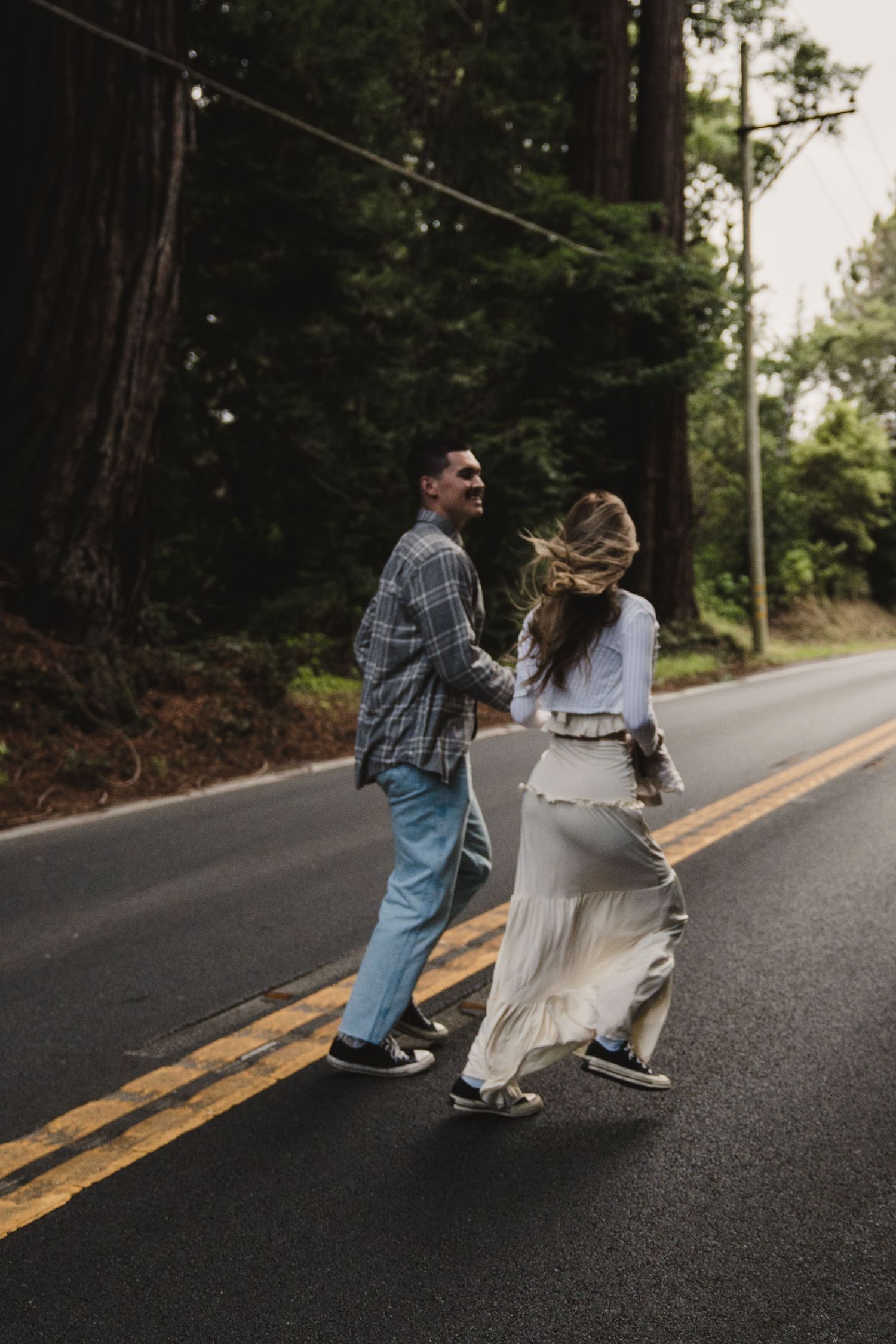 A couple dances playfully on a winding mountain road.