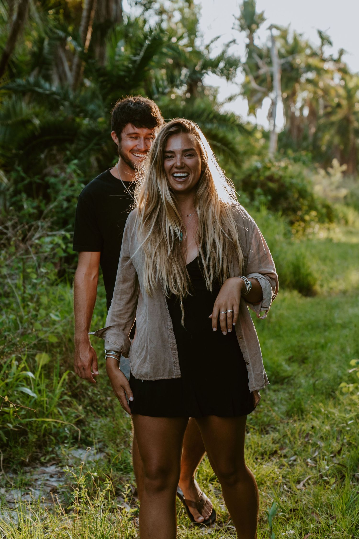 Couple sharing laughs and intimate moments while walking through a green tropical garden path.