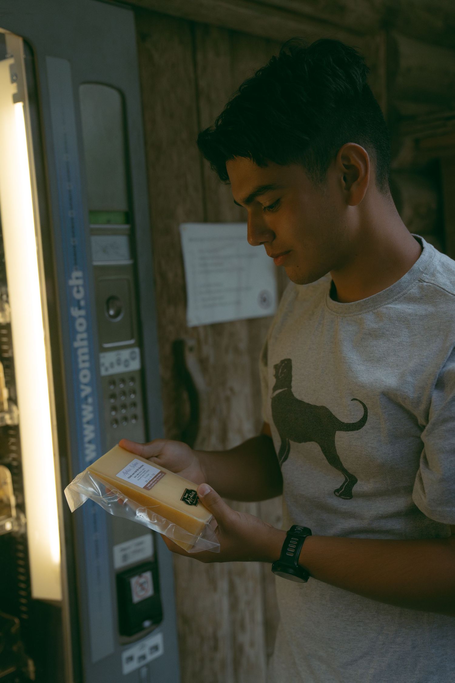 A person wearing a white t-shirt focuses intently on reading text from a mobile device in a dimly lit setting.