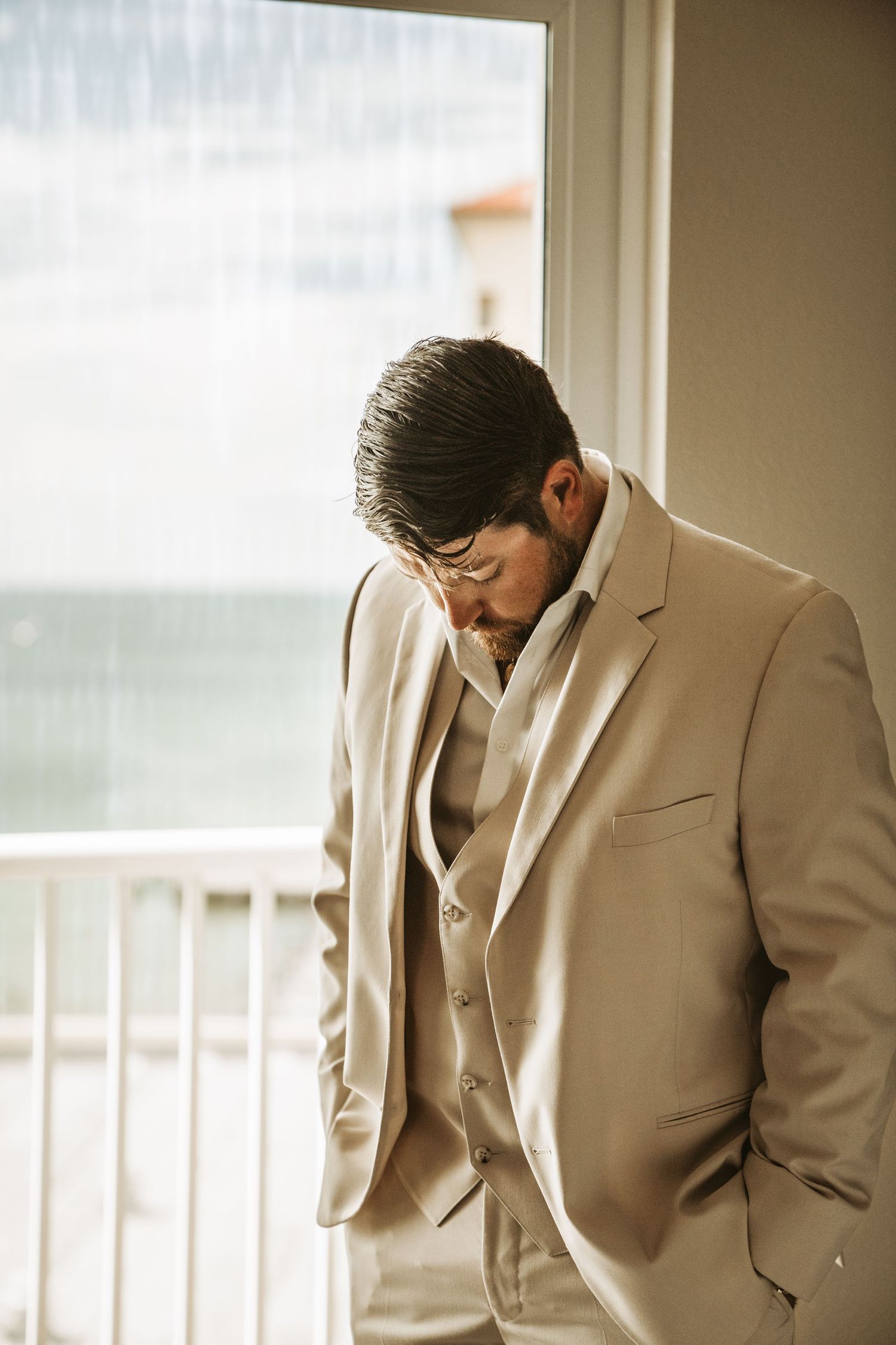 A person in a tan suit holds their head down in a sequence showing signs of depression and defeat.