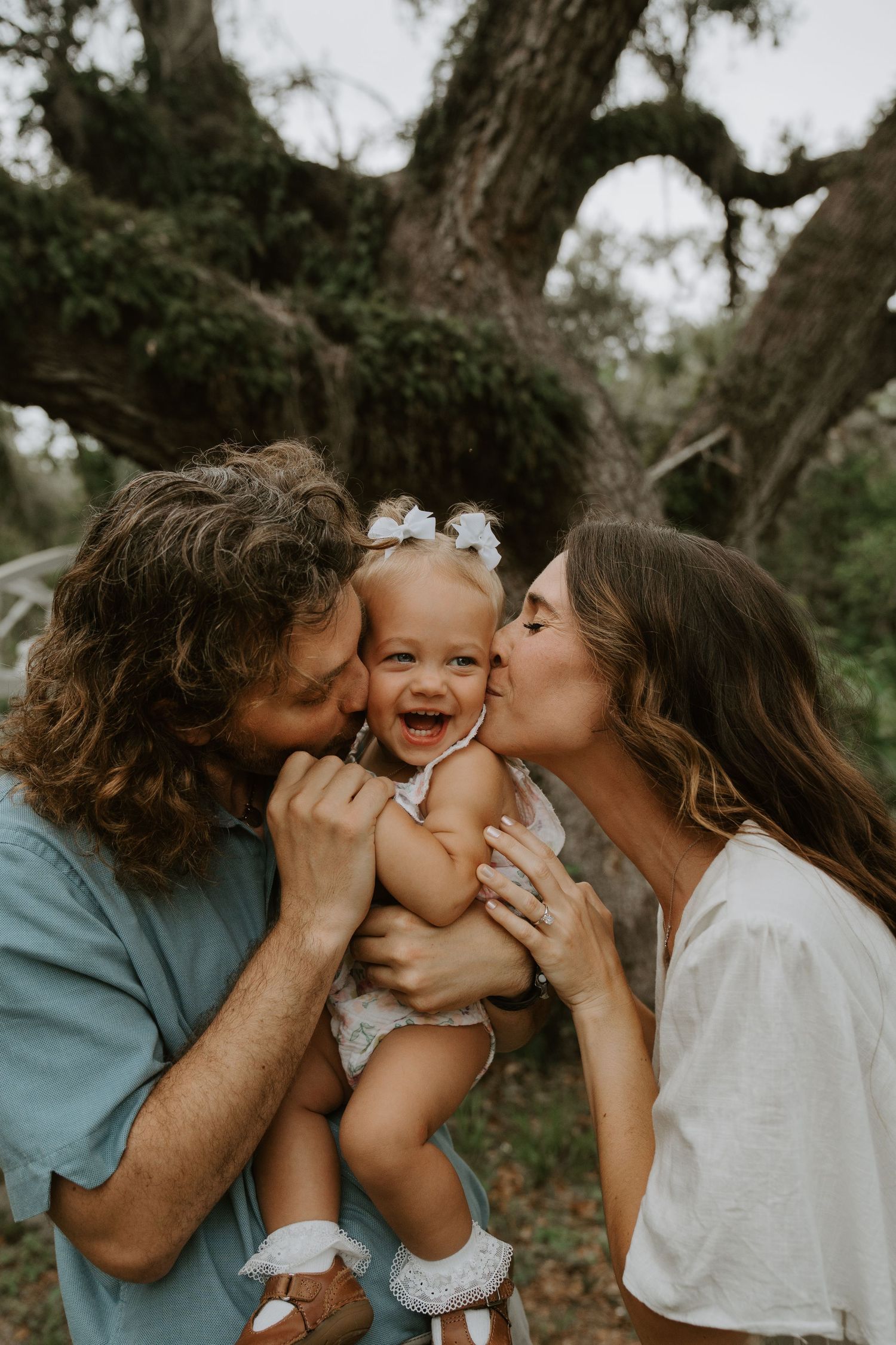 A sweet family moment sharing kisses and laughter outdoors.