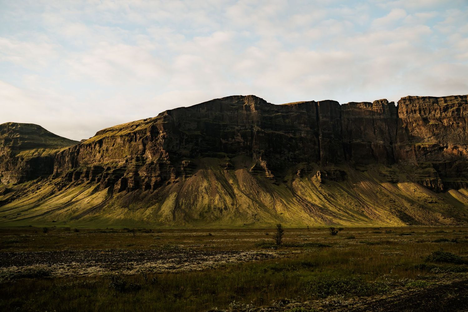 Panoramic view of rugged cliffs and mountains stretching across a desert landscape under a cloudy sky.