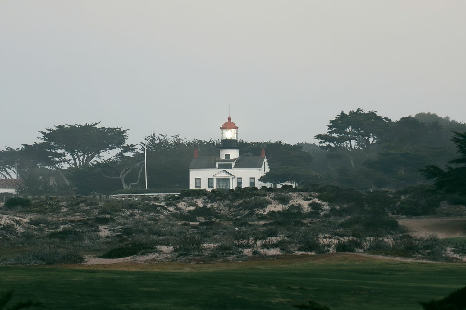 Panoramic coastal landscape with white church and buildings visible on distant hillside.