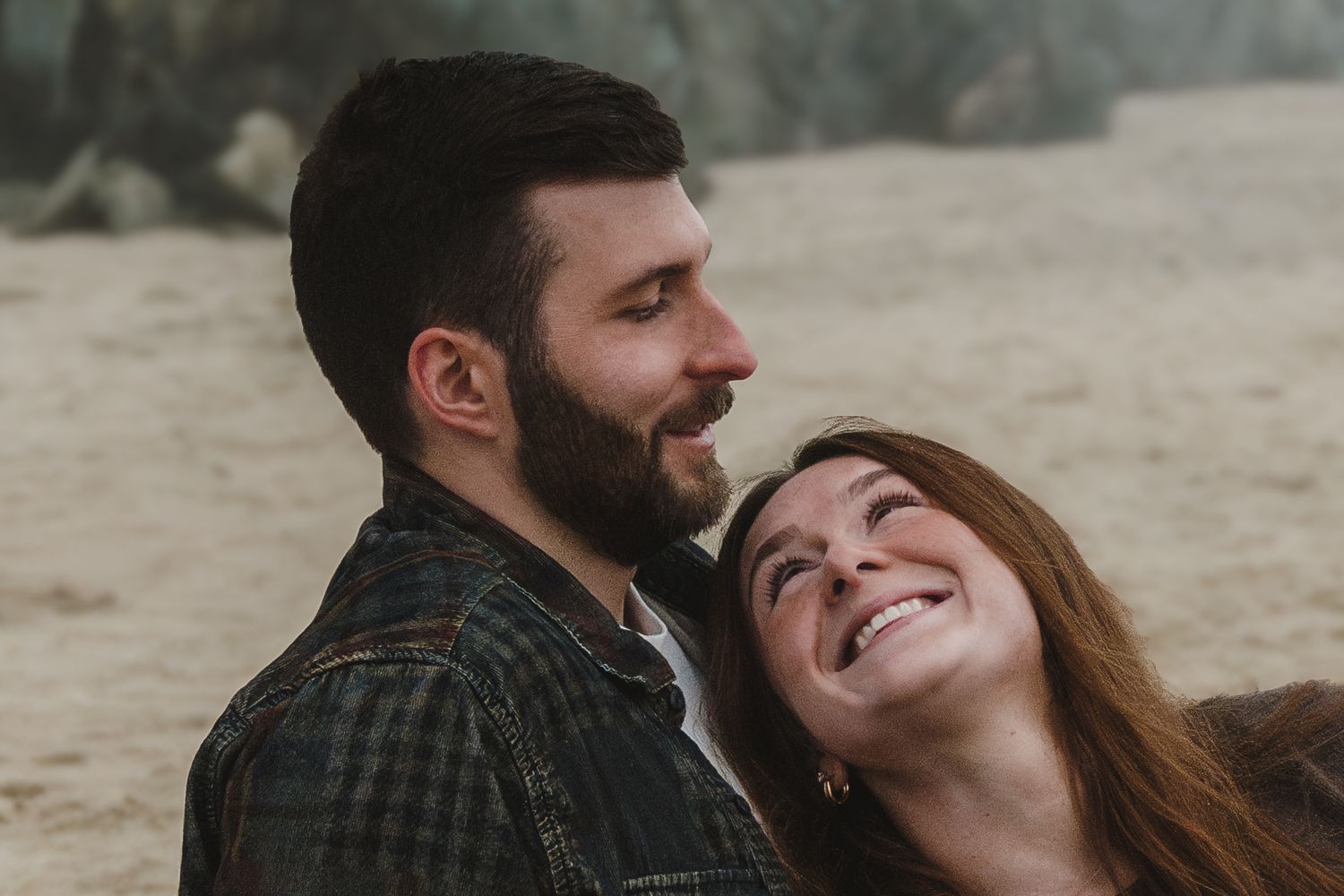 Two people share an intimate moment on a foggy beach.