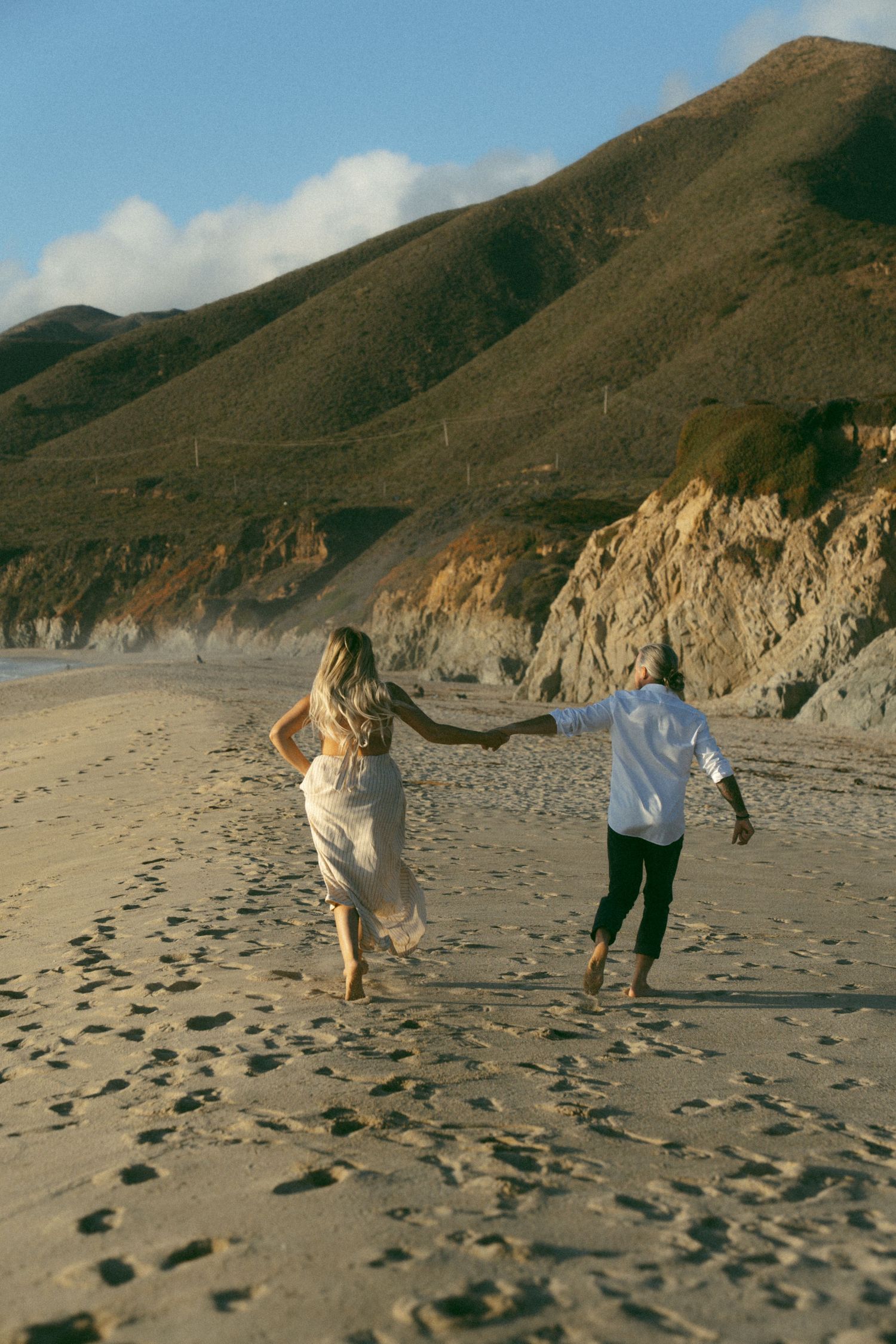 A sequence of action shots shows people walking on a beach with rocky cliffs, leaving footprints in the sand.