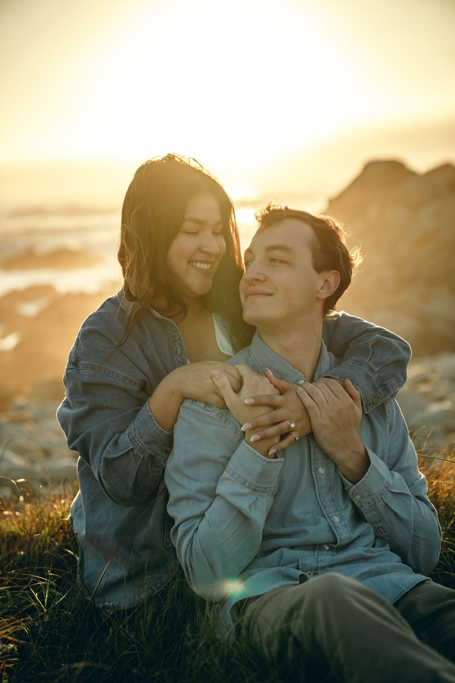 A couple shares tender moments together on a beach at sunset in matching denim outfits.
