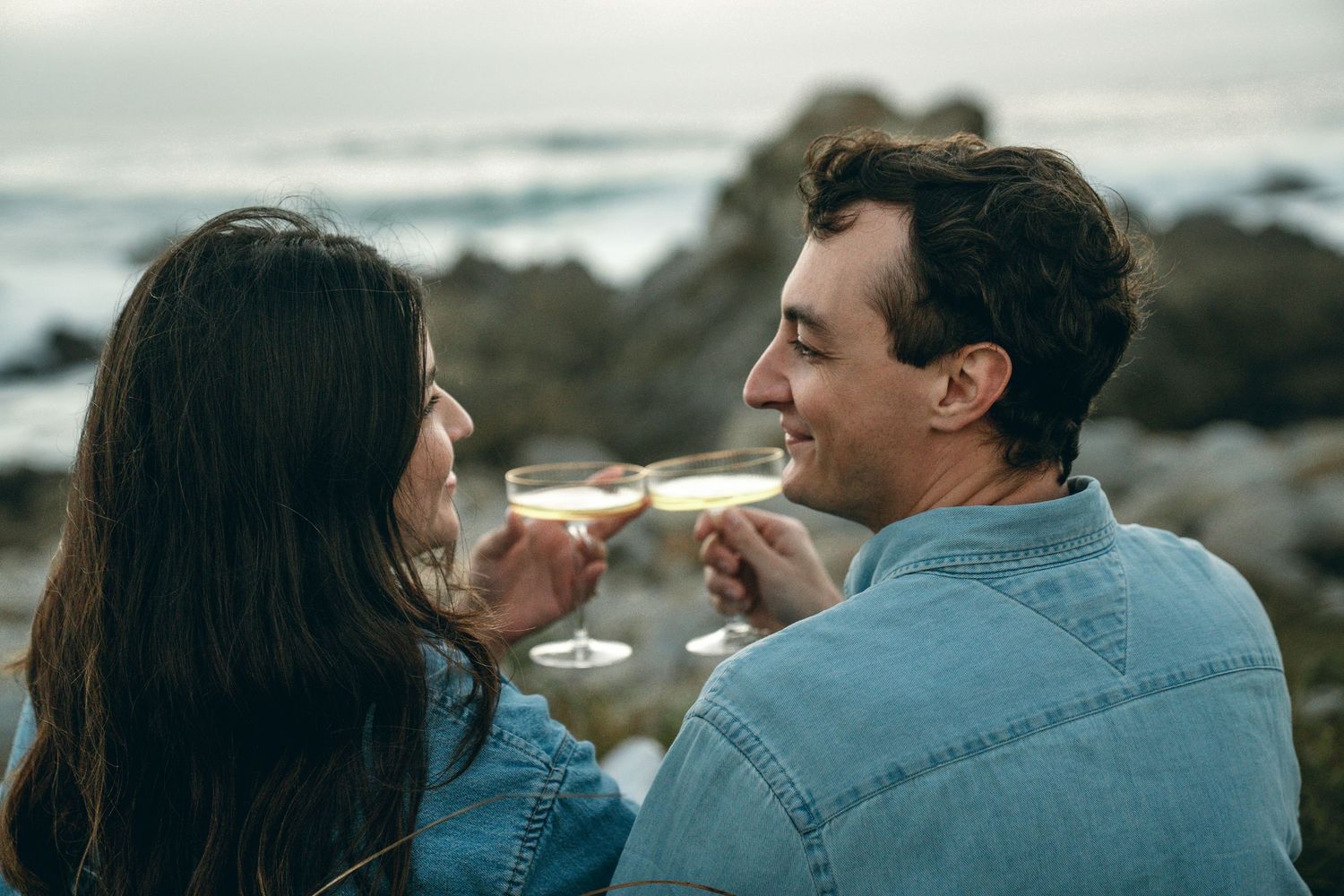 Couple sharing playful moments on scenic coastal overlook.
